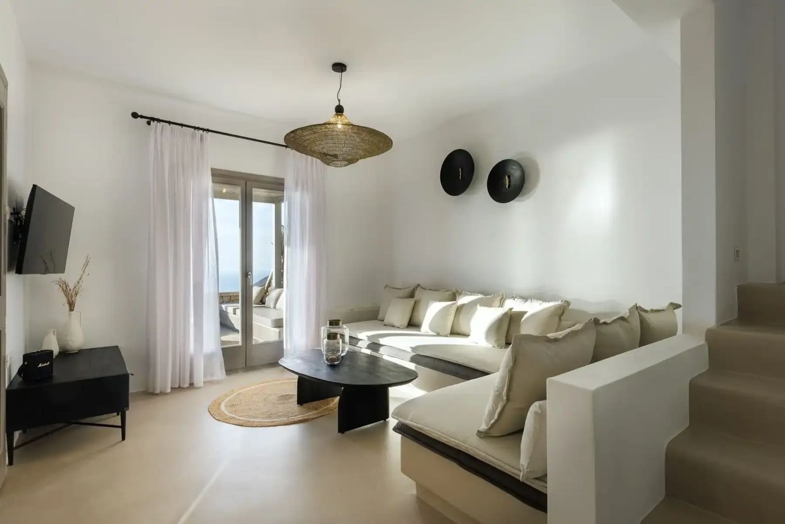 Wohnbereich mit großem Ecksofa, dunklem Couchtisch und Balkontür mit Blick aufs Meer.