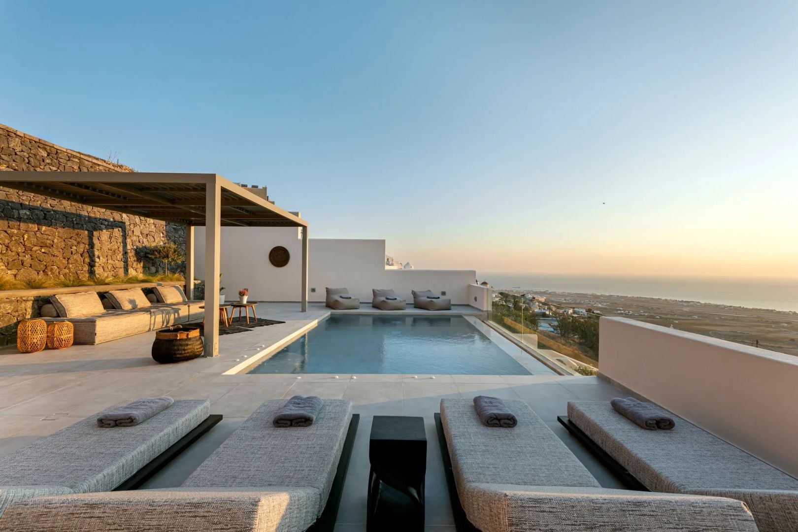 Außenbereich mit Pool, Liegestühlen und einer überdachten Lounge mit Blick auf die Küste.