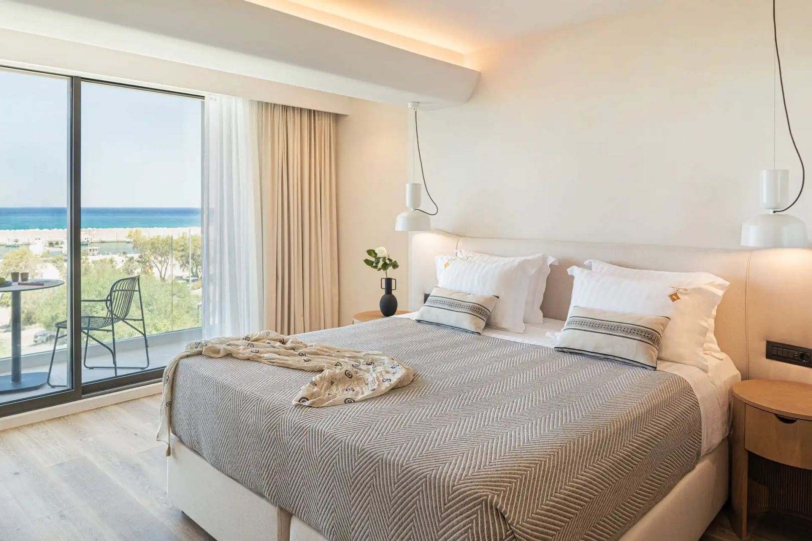 Modernes Doppelbett im hellen Hotelzimmer mit Ausblick auf das blaue Meer.