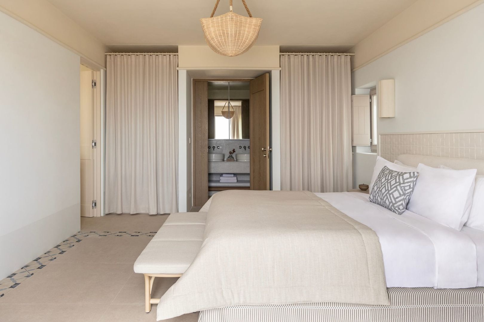 Helles Hotelzimmer mit Blick durch die Tür auf den Doppelwaschtisch im Bad