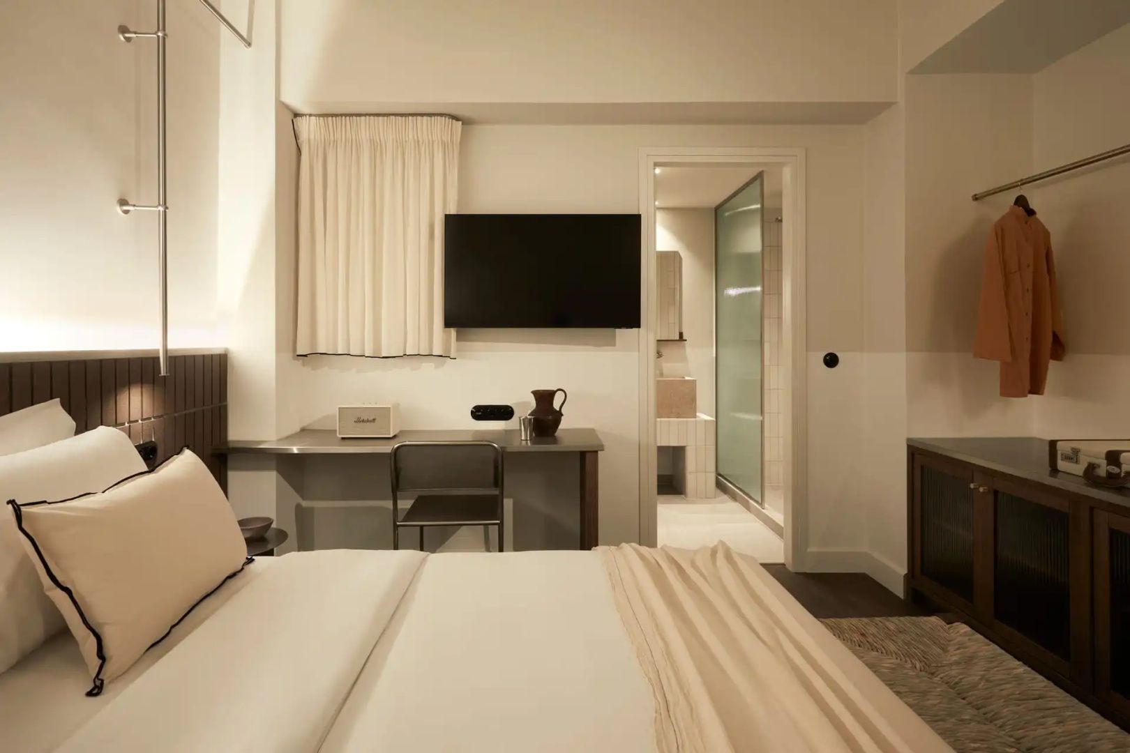 Blick vom Bett auf einen Schreibtisch mit Fernseher und den Durchgang zum Badezimmer.