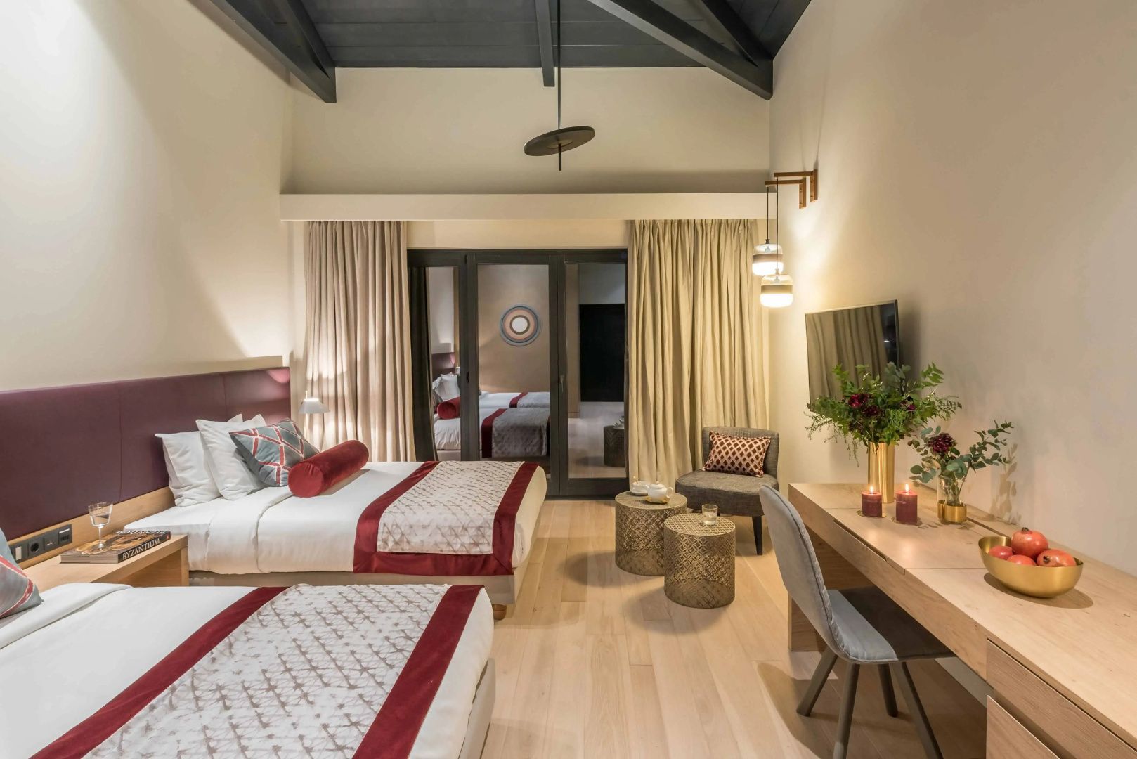 Geräumiges Hotelzimmer mit zwei Betten, Schreibtisch und Sitzbereich vor dem Balkon