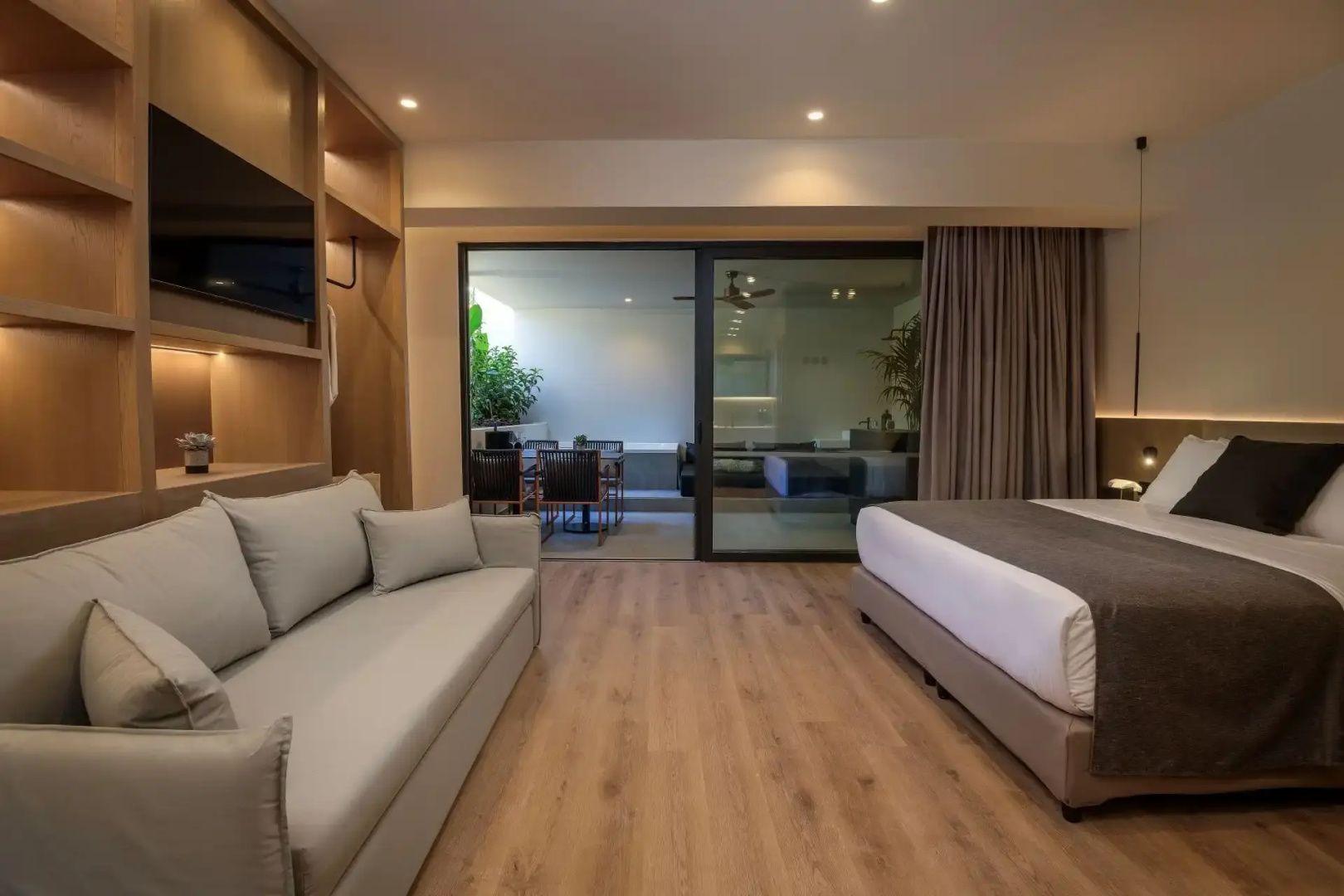 Geräumiges Hotelzimmer mit Sofa, Doppelbett und Zugang zur privaten Terrasse.