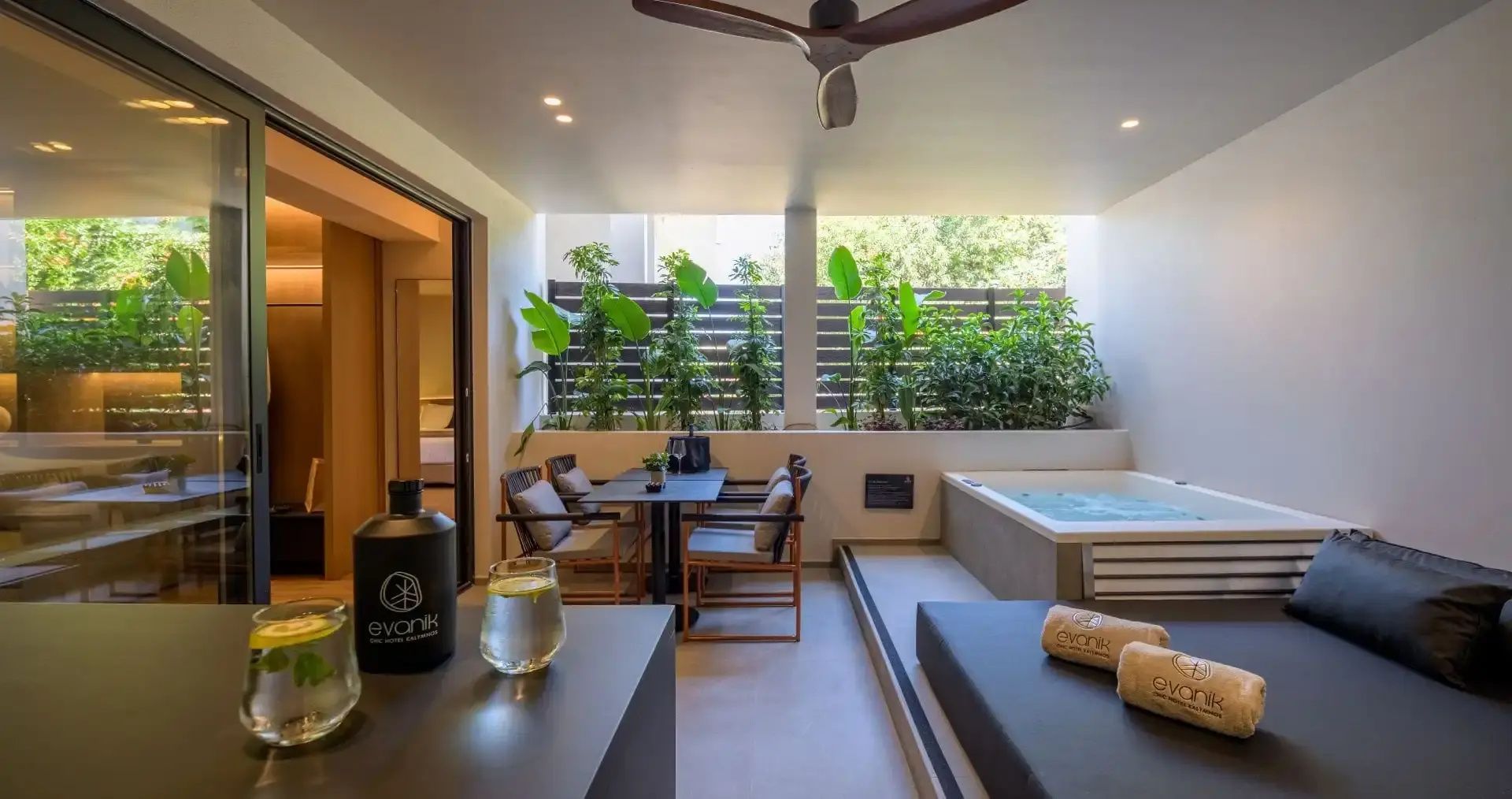 Überdachte Terrasse mit Whirlpool, Sitzgruppe, Pflanzen und Deckventilator.