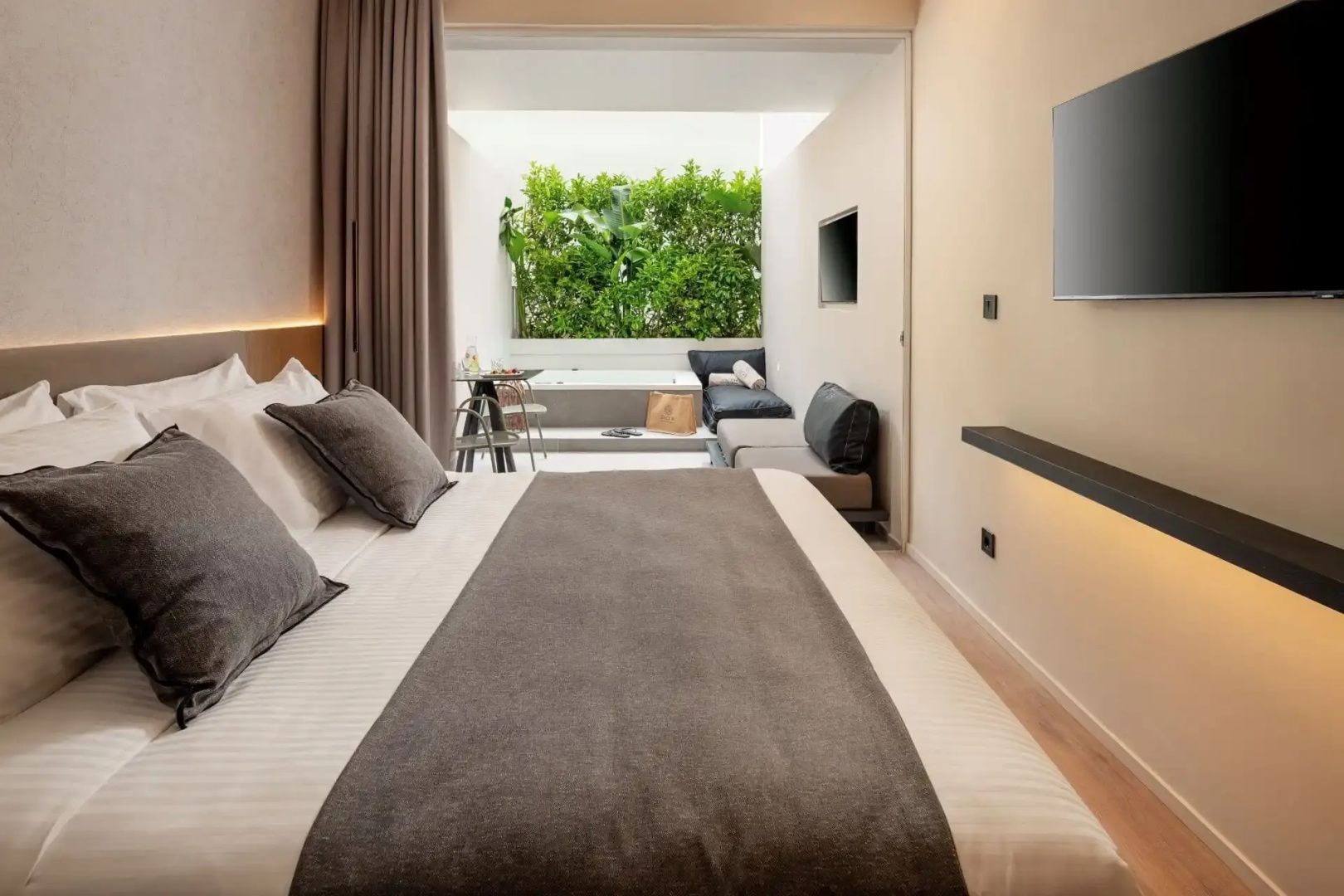 Hell eingerichtetes Hotelzimmer mit Doppelbett und direktem Zugang zum Terrassenbereich.