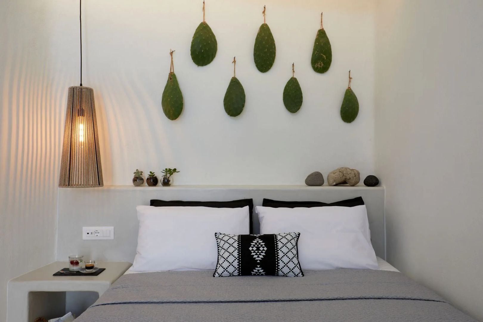 Bett mit weißen Kissen, Zierkissen und grüner Wanddekoration.
