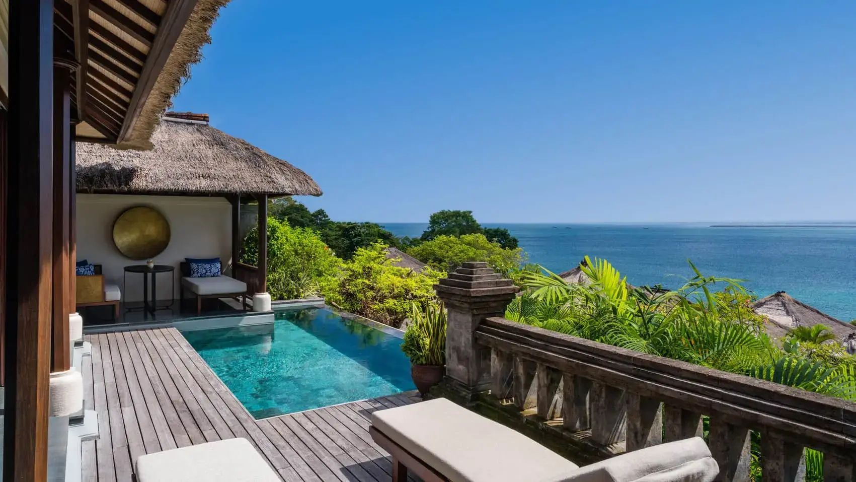 Terrasse einer Villa mit privatem Pool, Sonnenliege und Blick auf das Meer unter blauem Himmel.