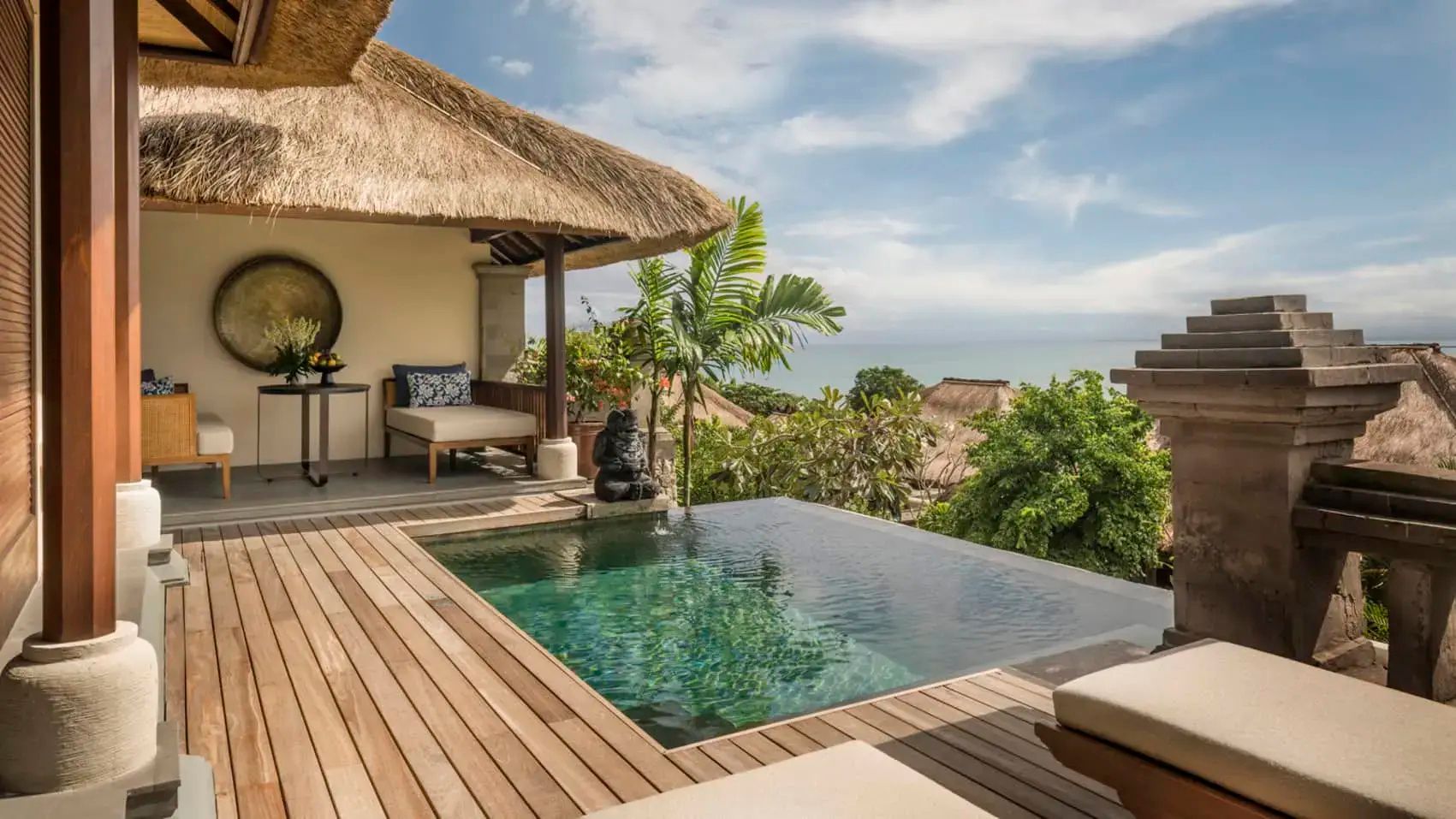 Privater Pool auf einer Holzterrasse mit Blick auf das Meer und tropische Pflanzen.