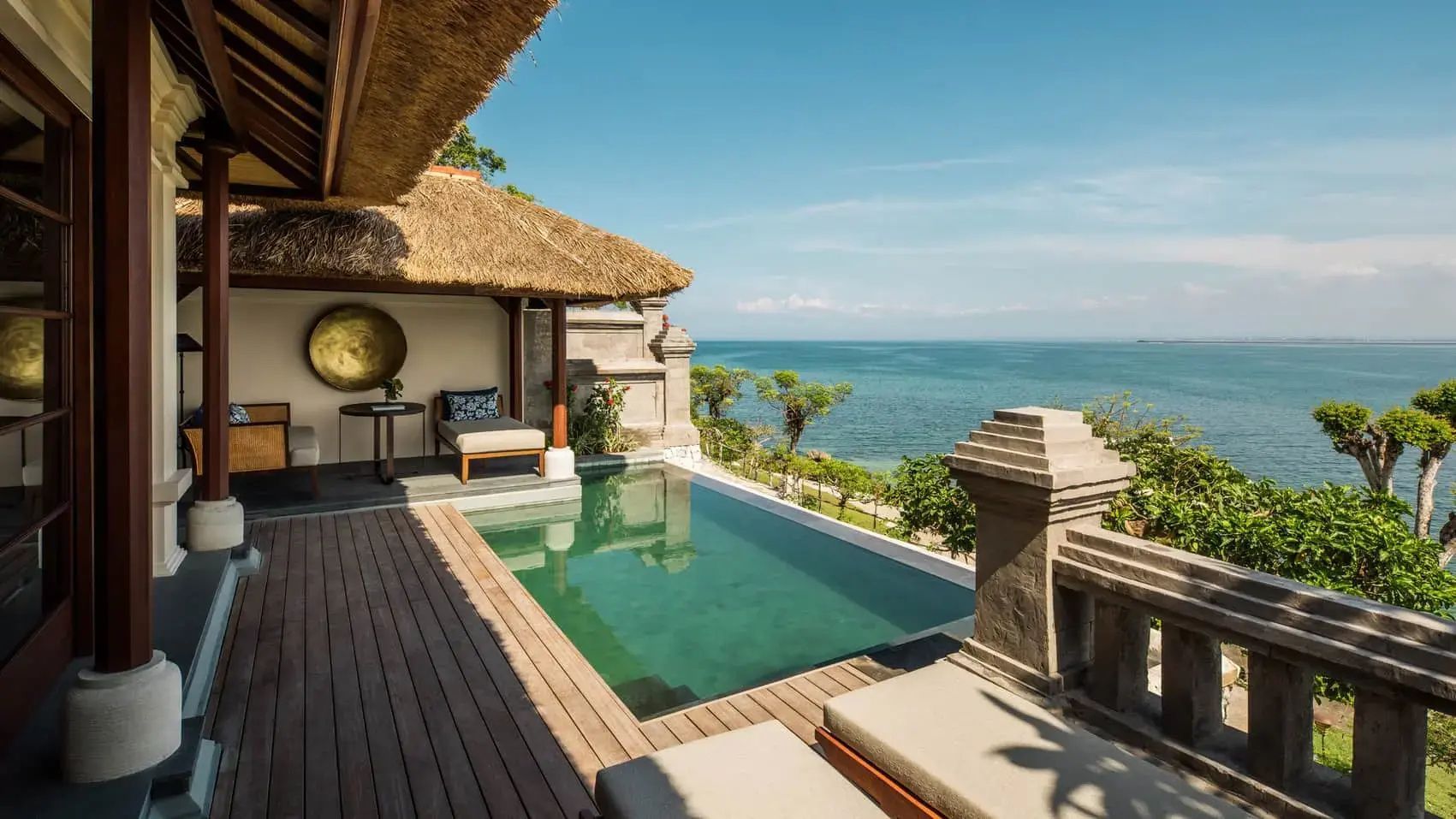 Private Terrasse mit Pool, Sonnenliege und Reetdach-Pavillon mit Blick aufs Meer.