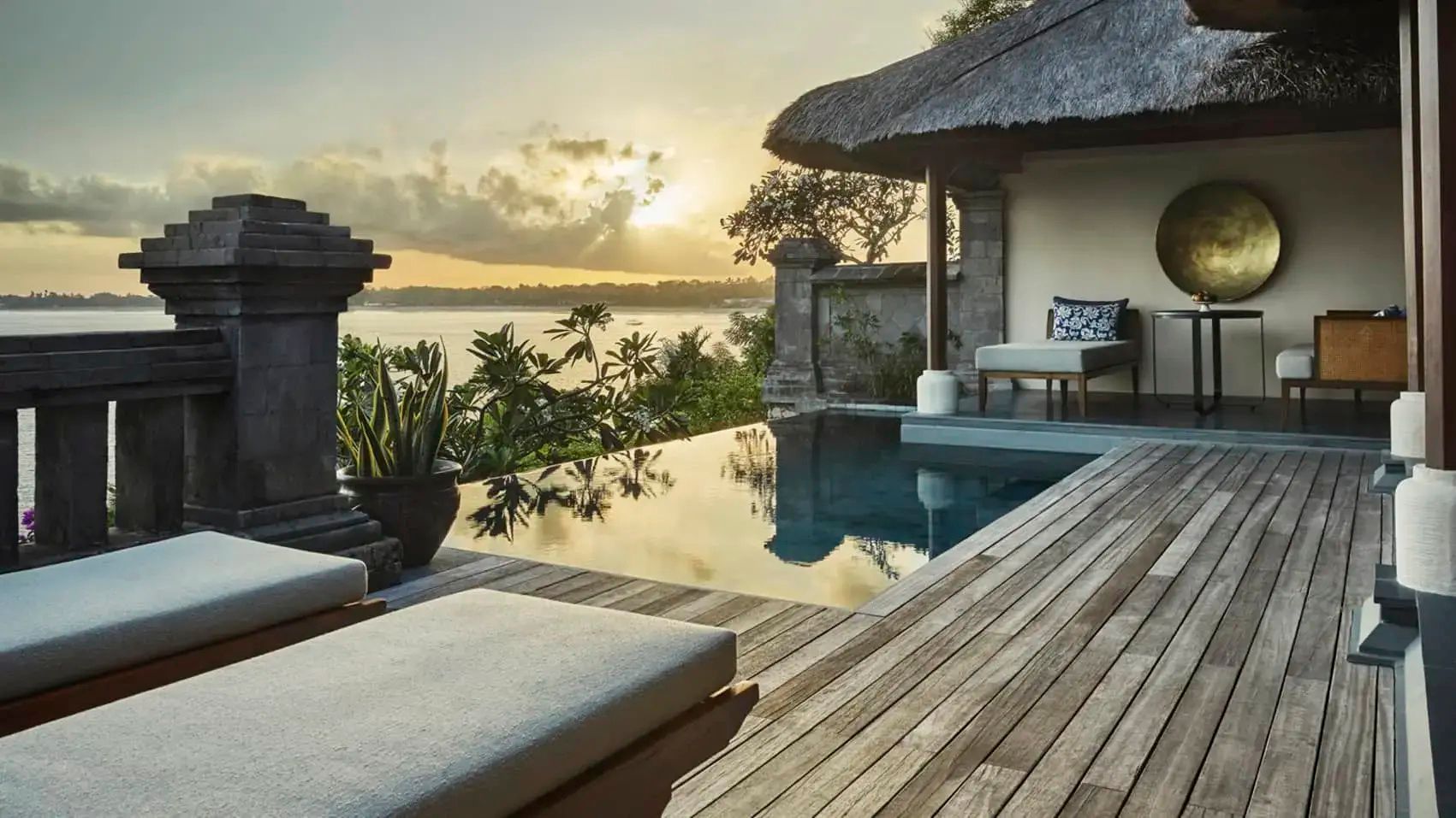 Holzterrasse mit privatem Infinity-Pool bei Sonnenuntergang und Blick auf die Bucht.