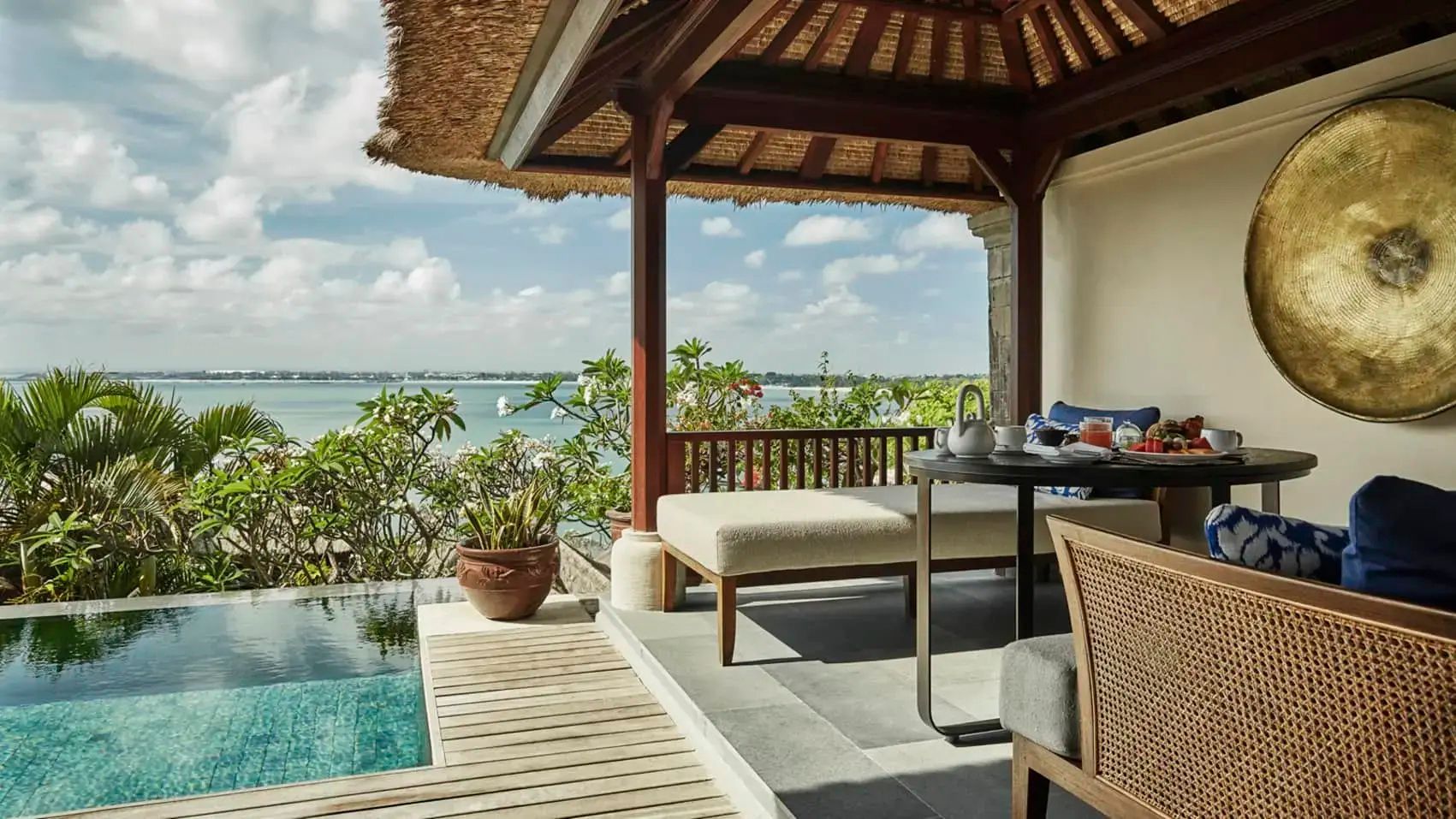 Überdachte Terrasse mit Tagesbett, Tisch, privatem Pool und Aussicht auf die Meeresbucht.