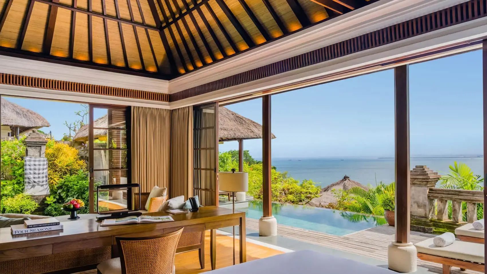 Blick aus der offen gestalteten Villa auf einen eigenen Pool und das dahinterliegende Meer.