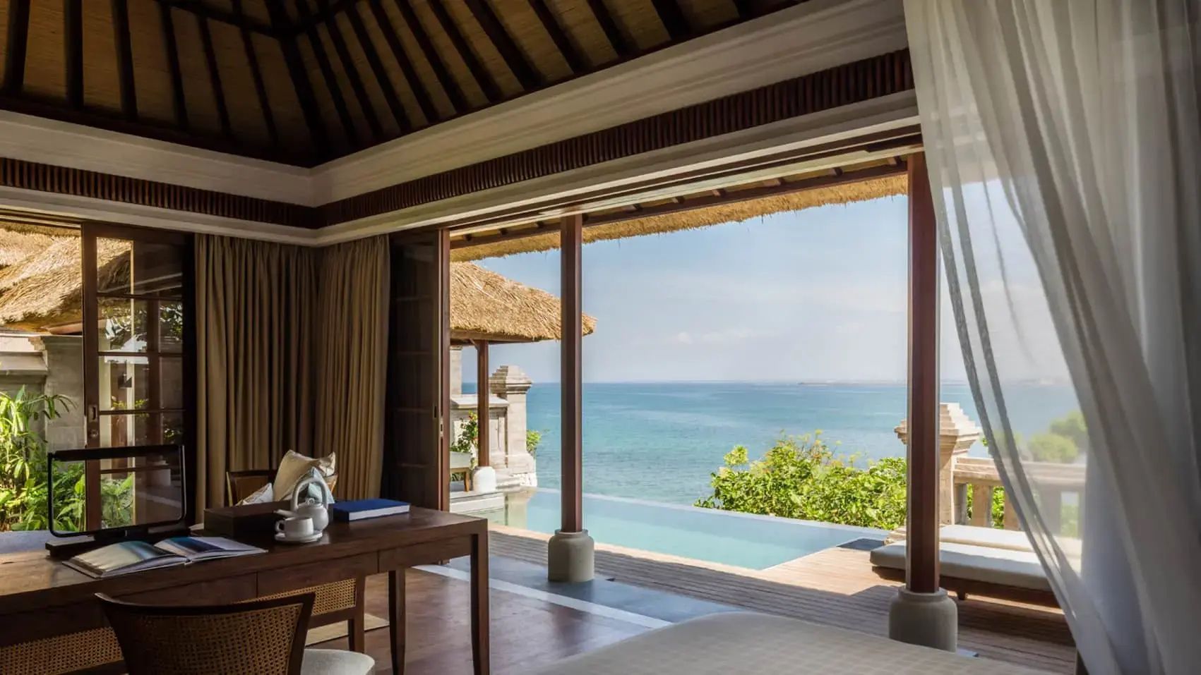 Blick aus dem Zimmer über den privaten Pool hinweg auf den blauen Ozean.