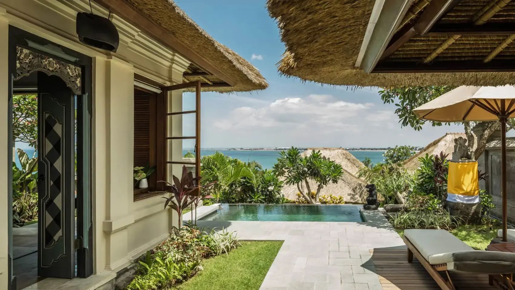 Privater Pool auf einer Villaterrasse mit Blick auf das Meer und Strohdächer.