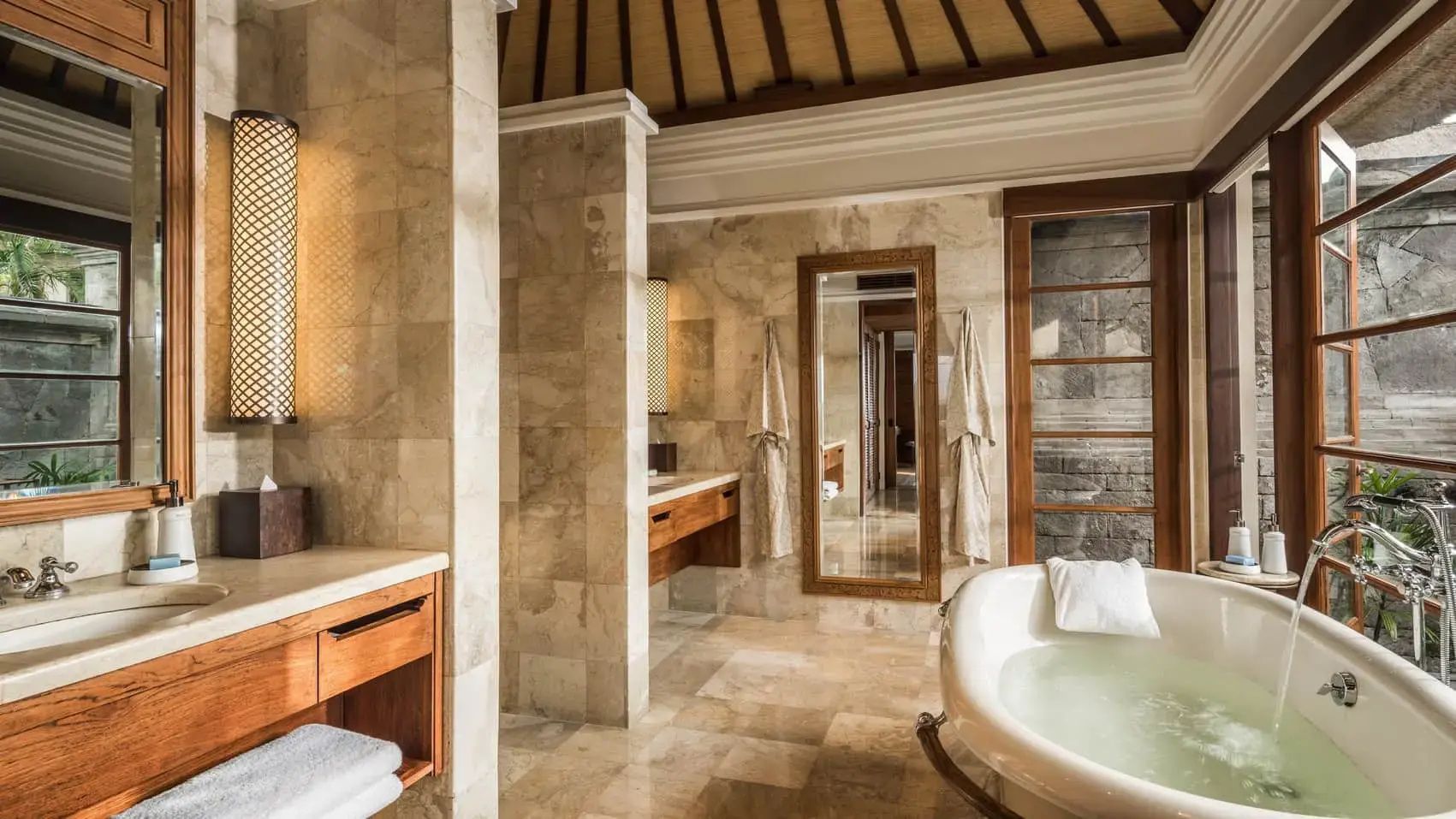 Geräumiges Badezimmer mit Marmorfliesen, Holzwaschtisch und freistehender Badewanne.