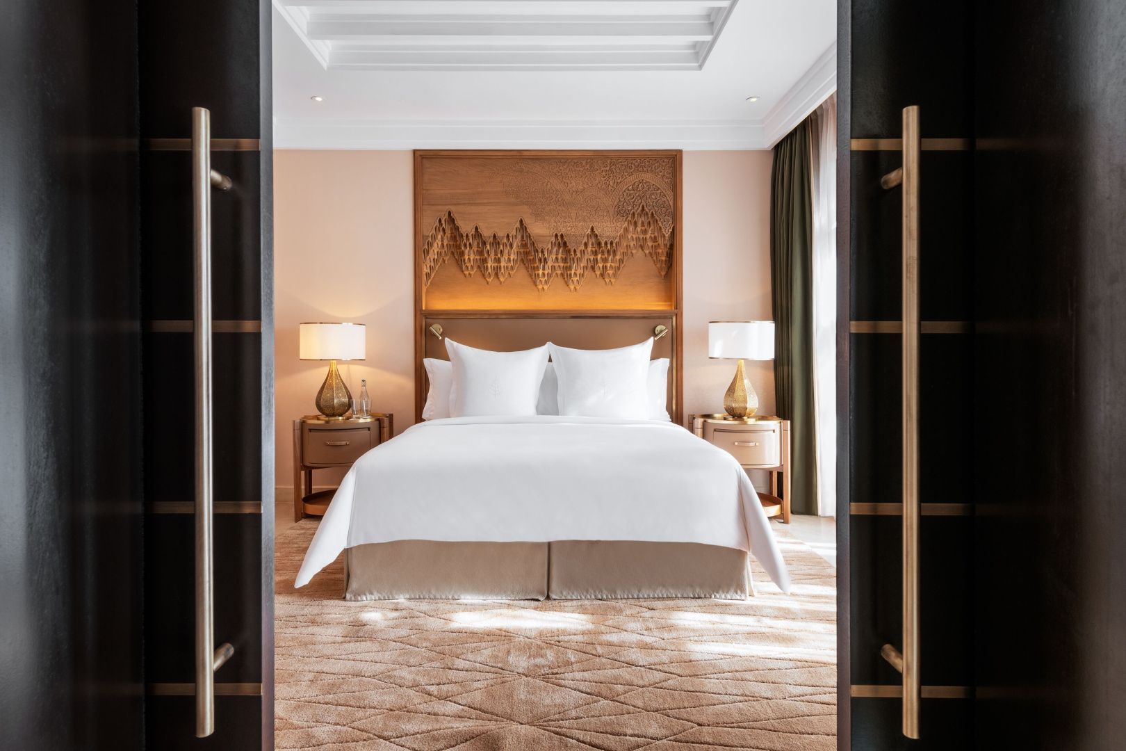 Doppelbett mit weißer Bettwäsche, Nachttischen und dekorativer Holzverkleidung im Hotelzimmer.