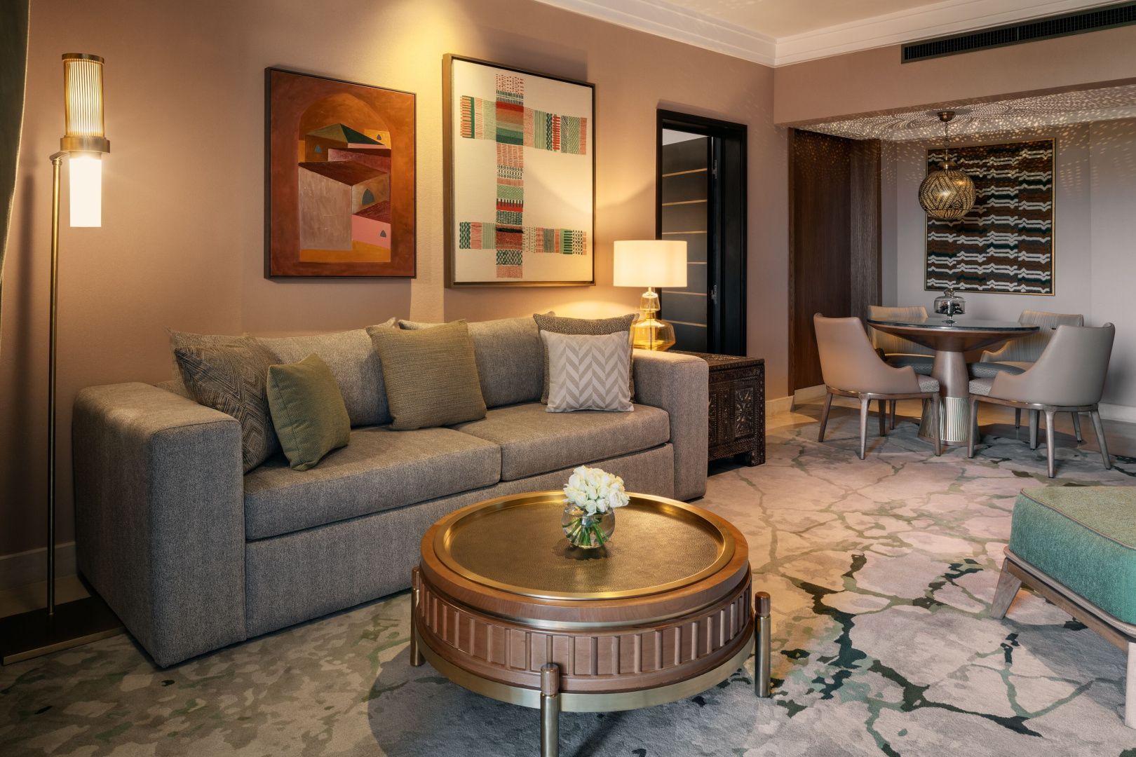 Wohnbereich einer Suite mit grauem Sofa, rundem Couchtisch und Wandbildern.