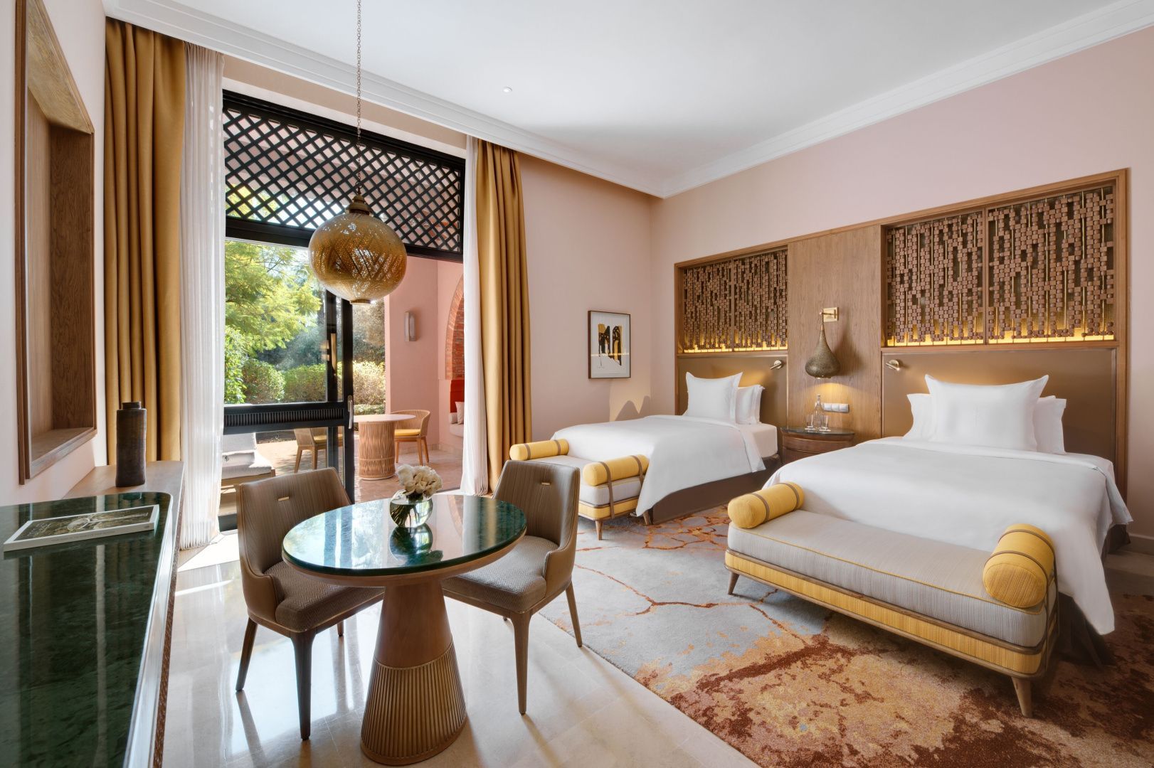 Schlafzimmer mit zwei Einzelbetten, kleinem runden Tisch und Balkontür zum Außenbereich.