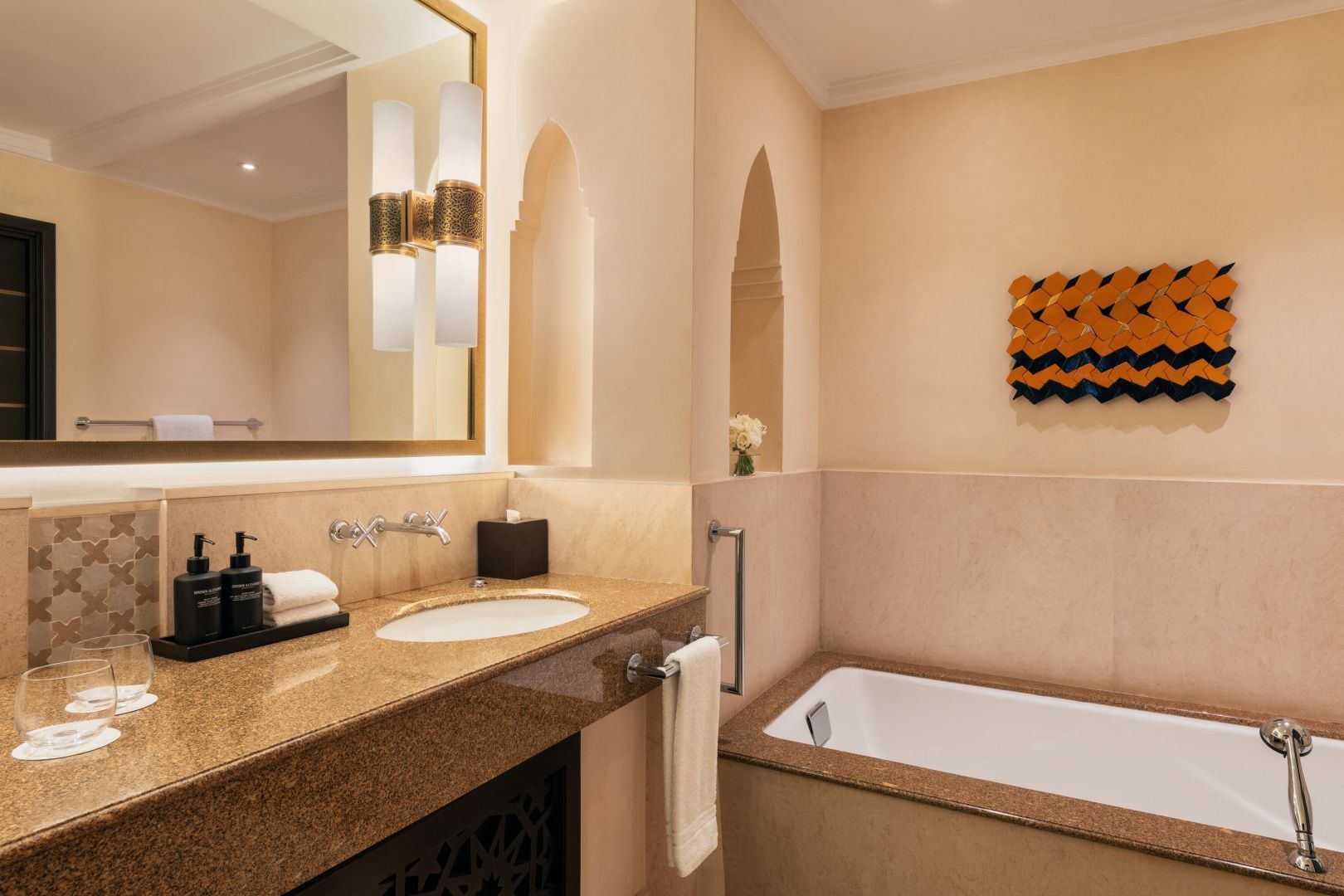 Waschtisch mit Granitplatte, Spiegel und eine eingelassene Badewanne in einem hellen Badezimmer.