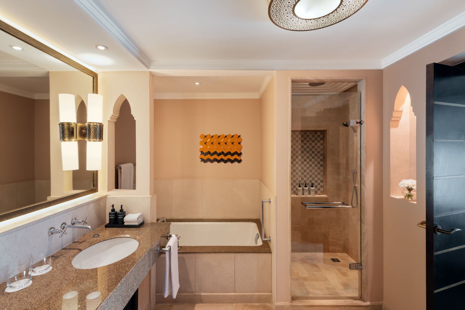 Badezimmer mit Waschtisch, großer Badewanne und einer separaten Dusche mit Glasabtrennung.