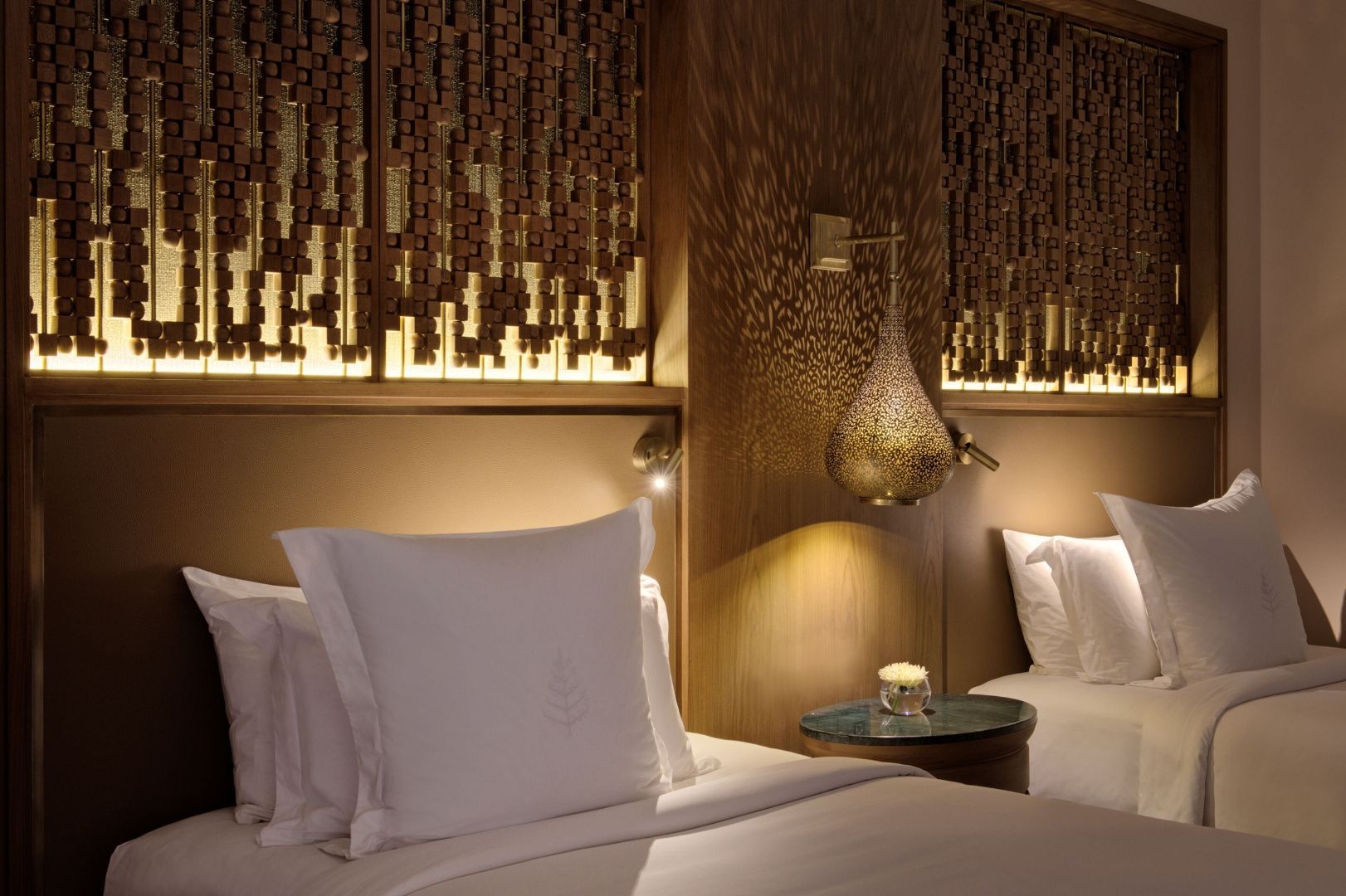 Nahaufnahme einer orientalischen Metalllampe und Kissen an einer Holzwand im Hotelzimmer.