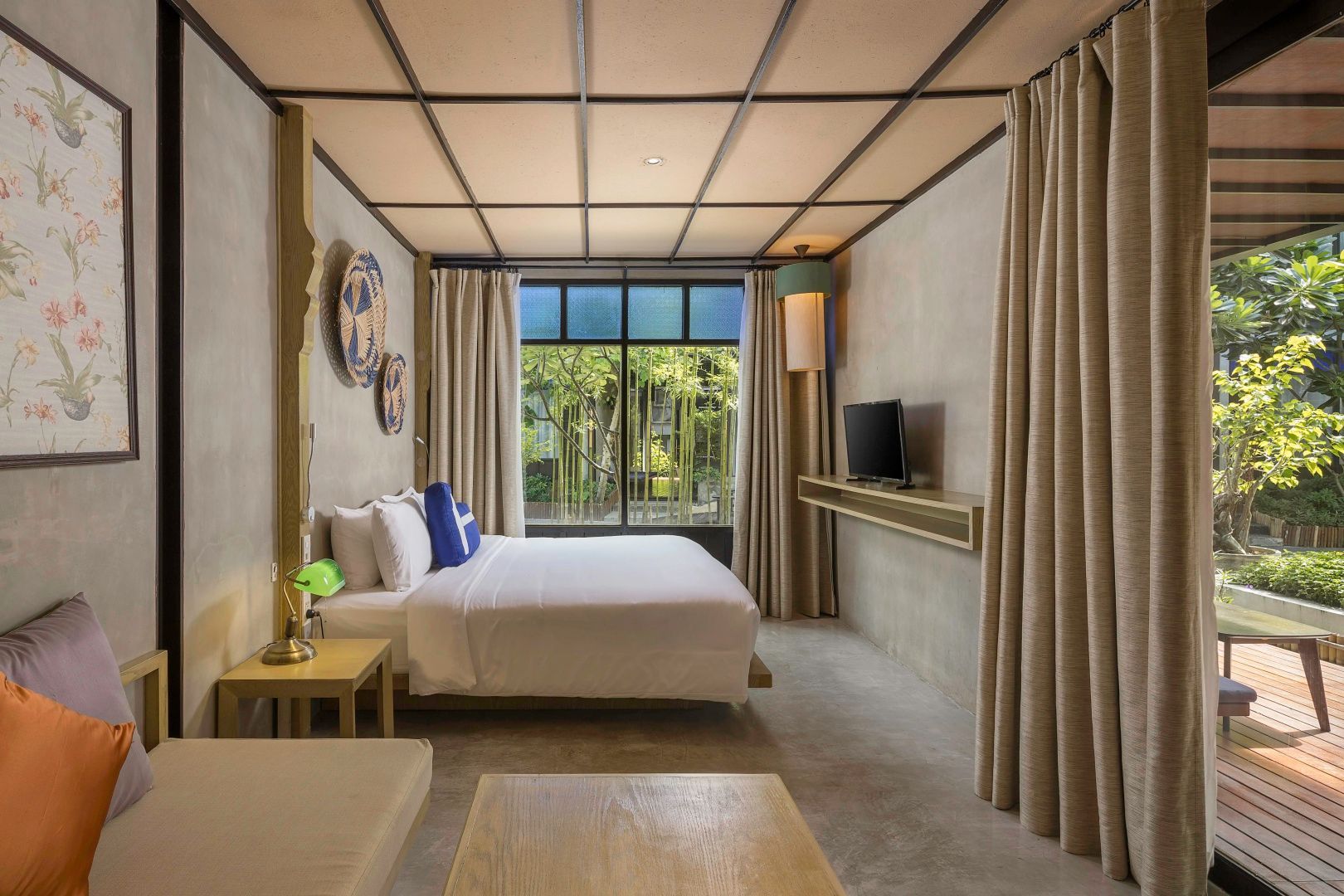 Hell gestaltetes Zimmer mit Doppelbett, Holzdecke und großem Fenster zum Garten.