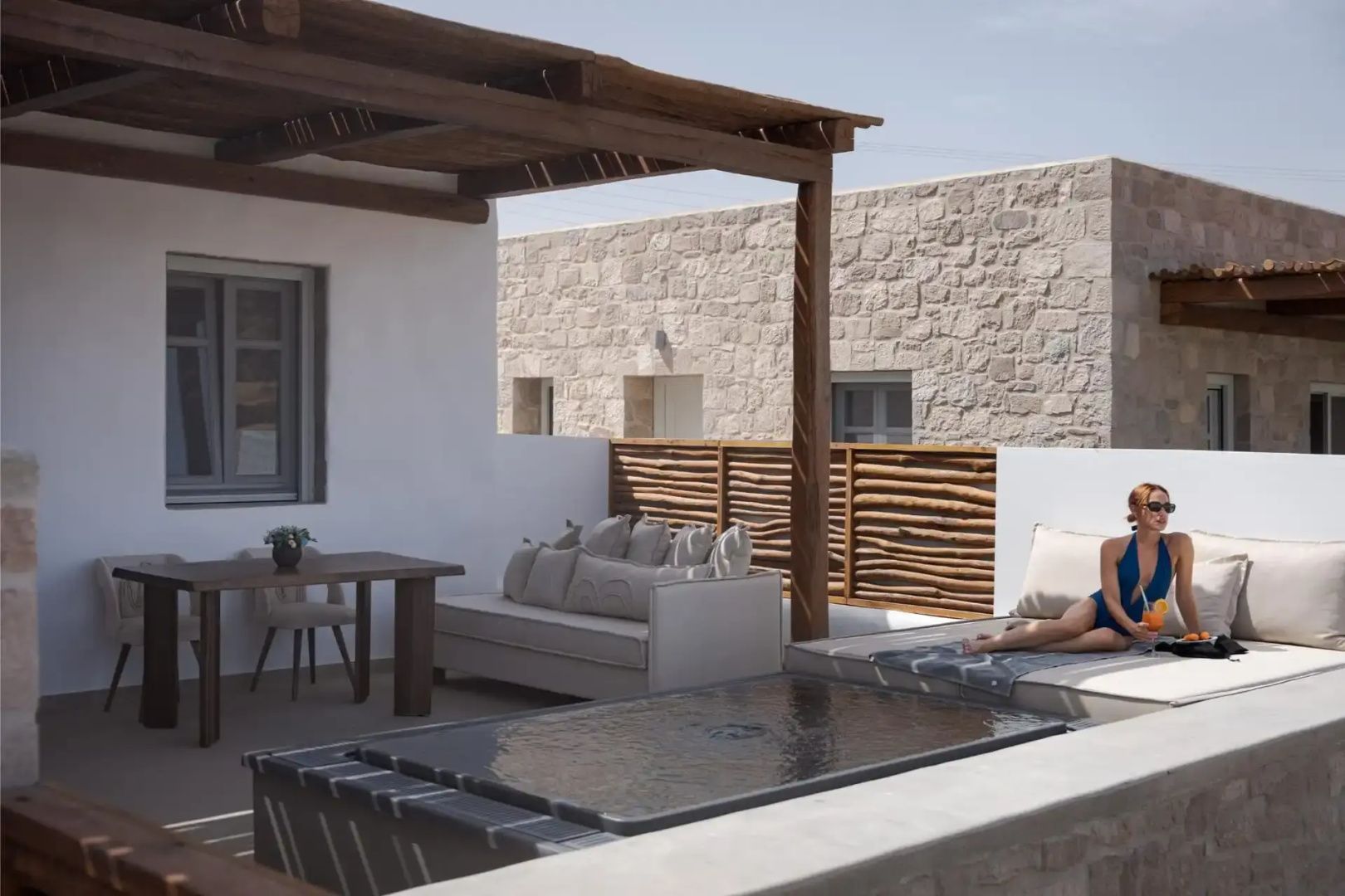 Sonnengeschützte Terrasse mit einer Holzpergola, Sitzmöbeln und einem integrierten kleinen Pool.