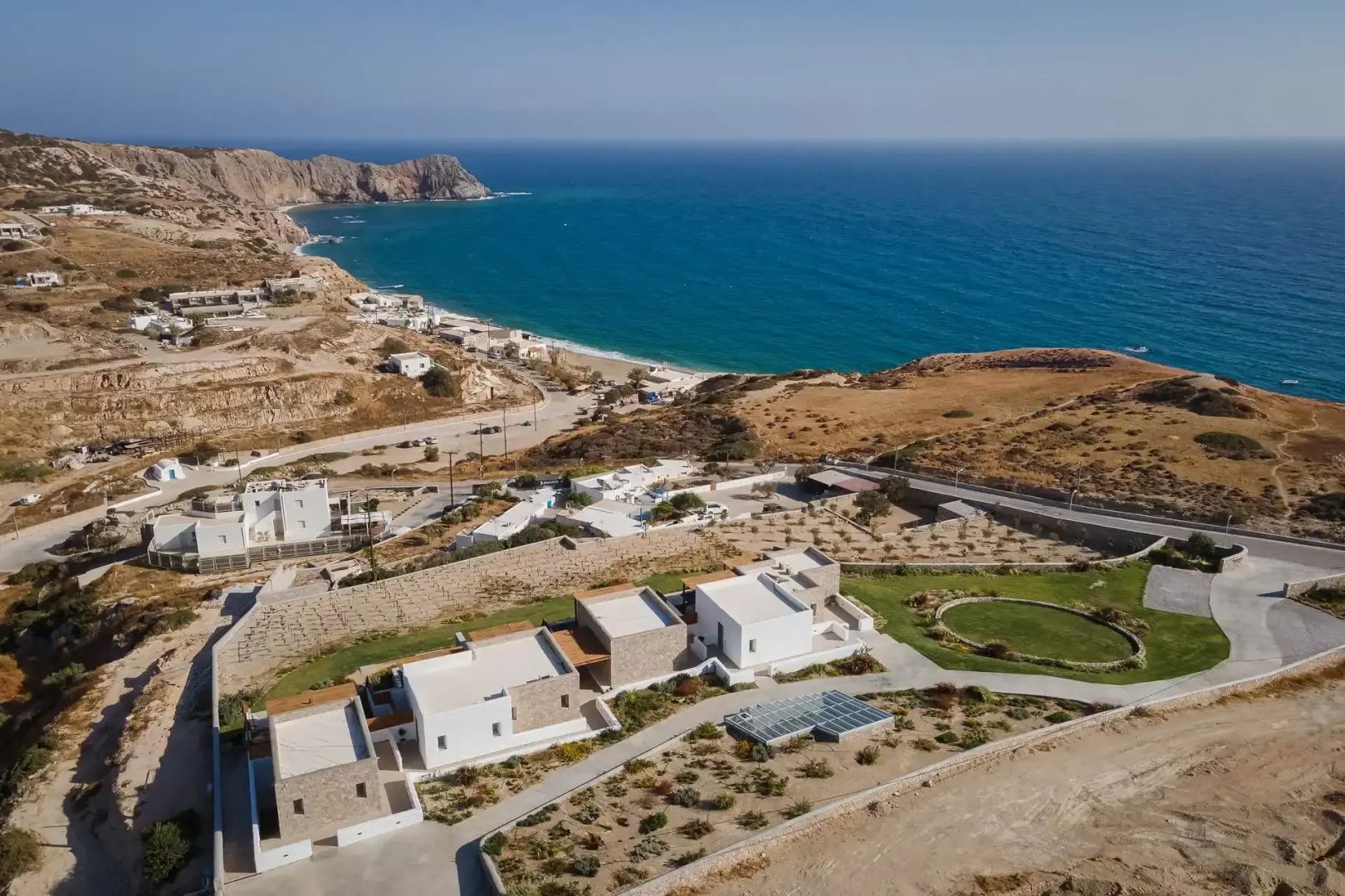 Luftaufnahme einer Hotelanlage mit Steinbauten an der Küste und Blick auf das Meer.