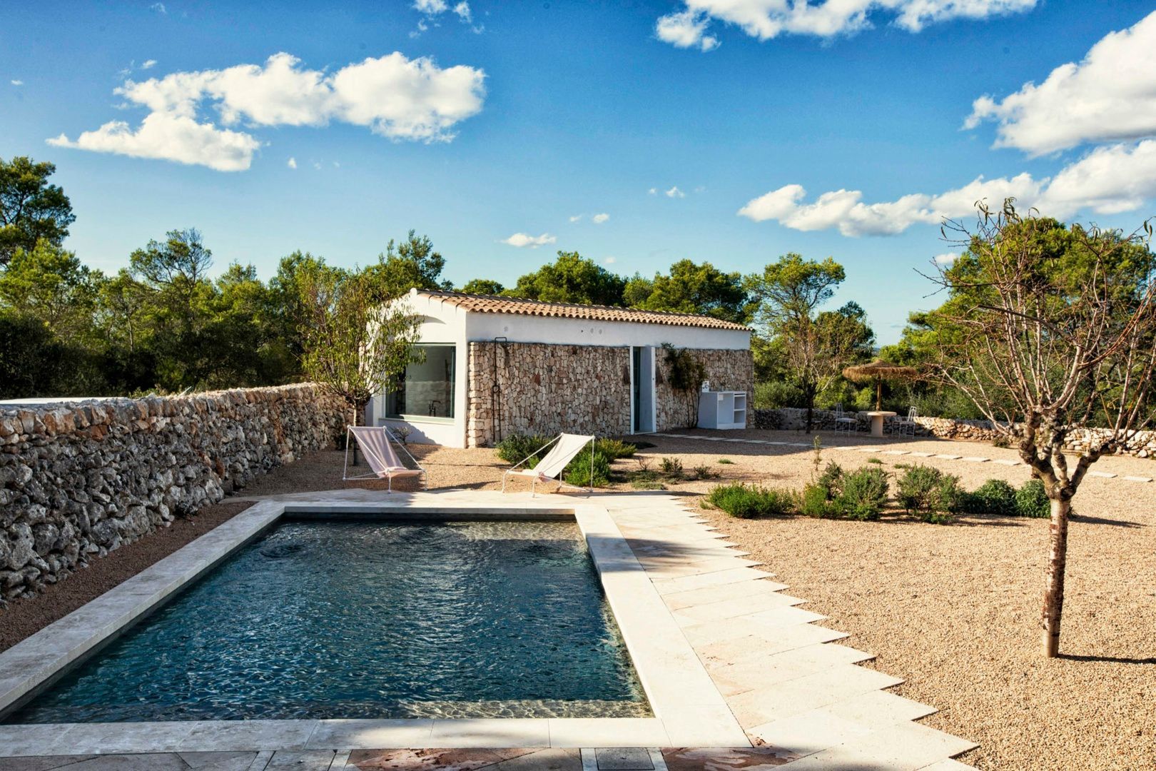 Kleines Steinhaus mit privatem Pool, Liegestühlen und von Bäumen umgebener Terrasse.