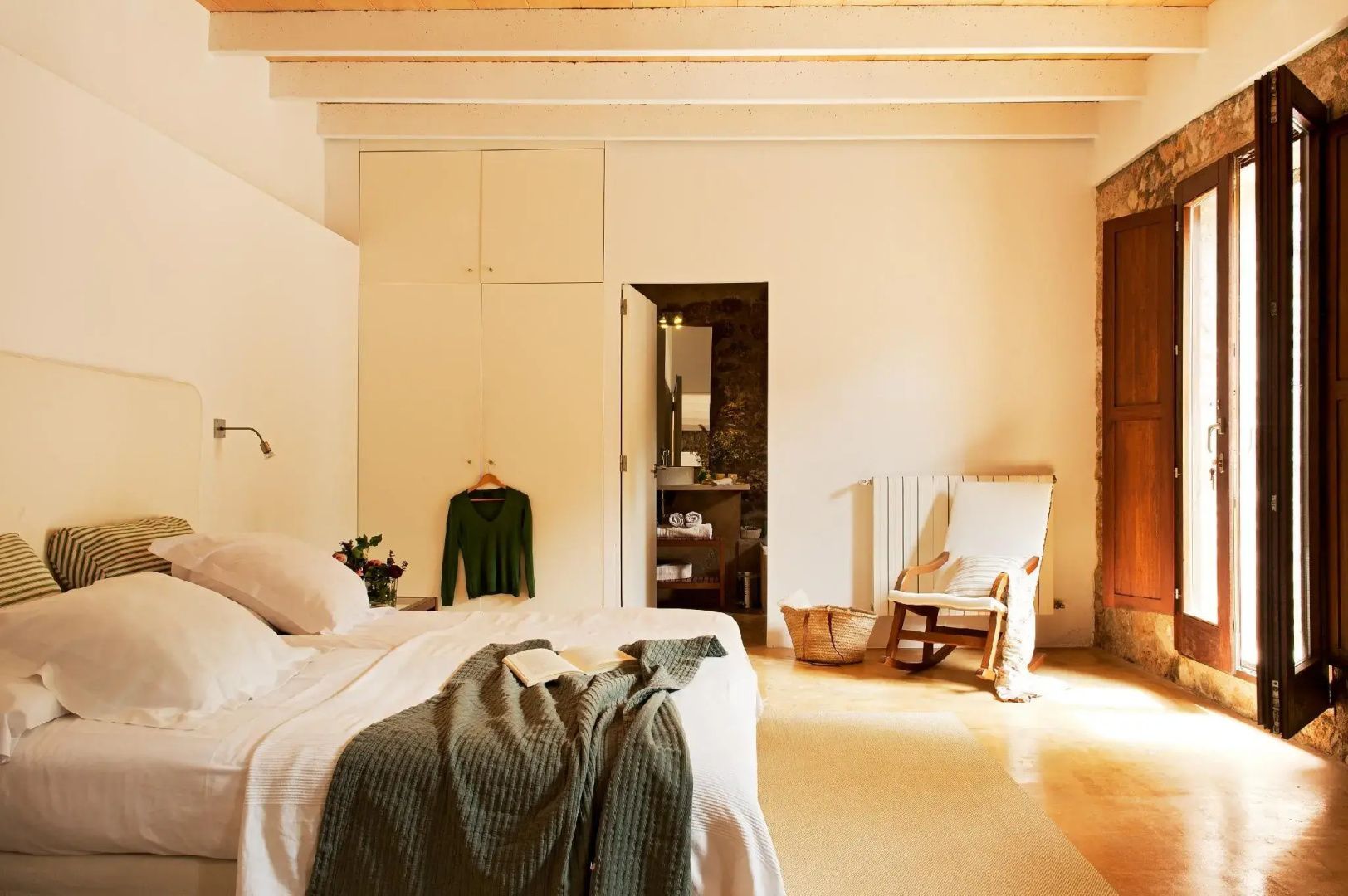 Schlafzimmer mit weißem Einbauschrank, Doppelbett und Schaukelstuhl.