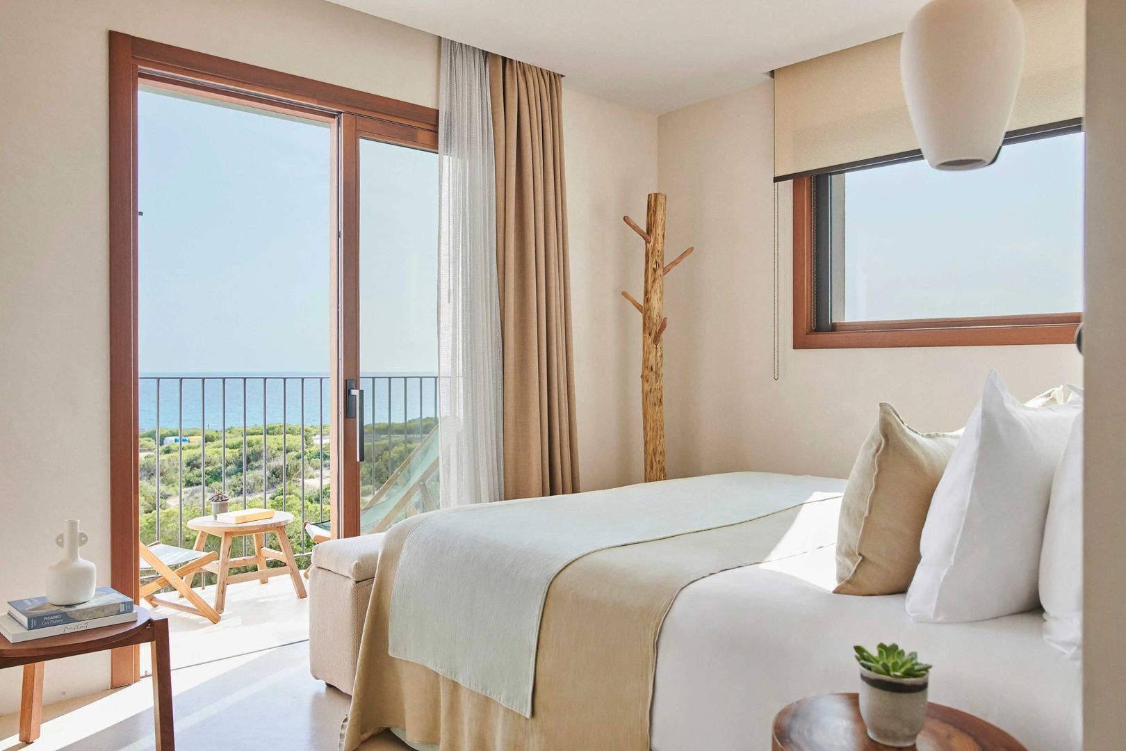 Hotelzimmer mit Blick durch die geöffnete Balkontür auf das Meer und die Küste.