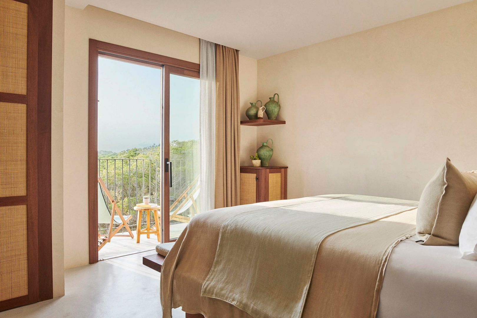 Schlafzimmer mit Doppelbett und geöffneter Balkontür mit Blick ins Grüne.