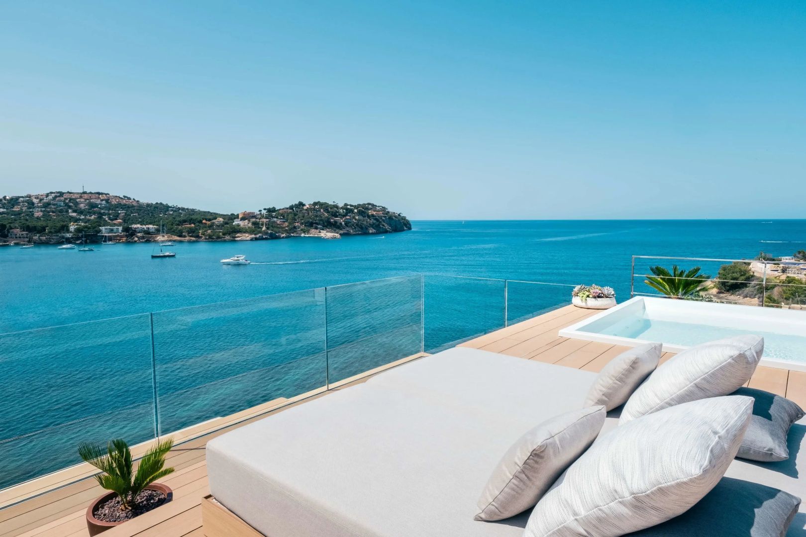 Sonnendeck mit Liegebett und kleinem Pool mit freiem Blick auf das Meer und die Küste.