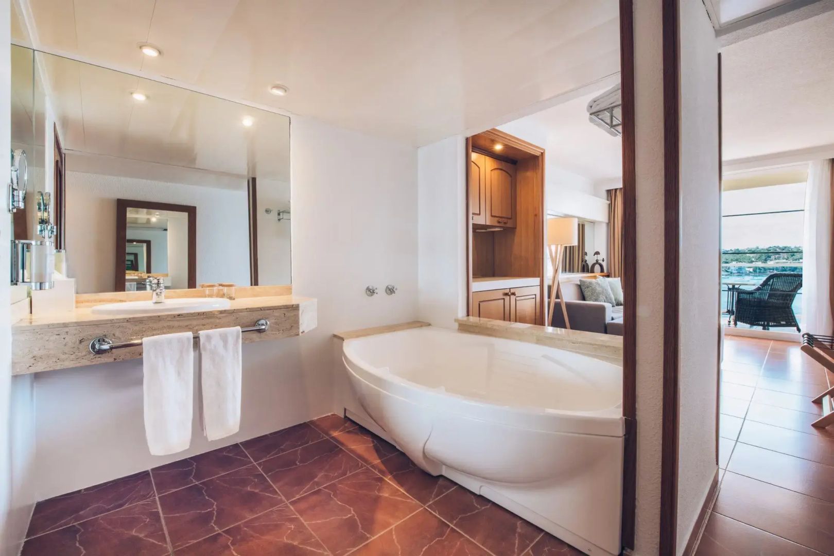 Badezimmer mit großer Badewanne, Waschtisch und großem Spiegel.