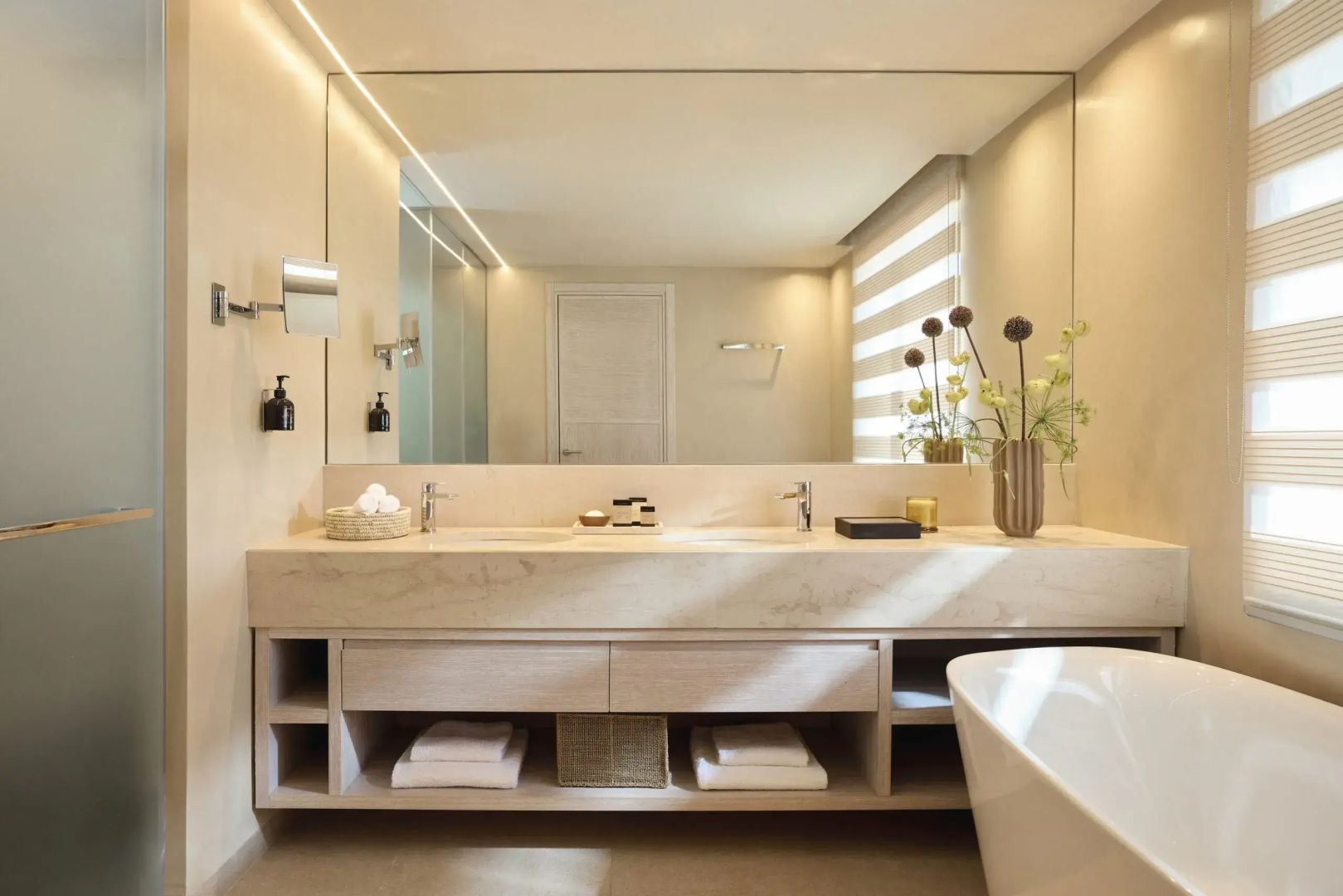 Modernes Badezimmer mit Doppelwaschtisch, großem Spiegel, Handtüchern und freistehender Badewanne.