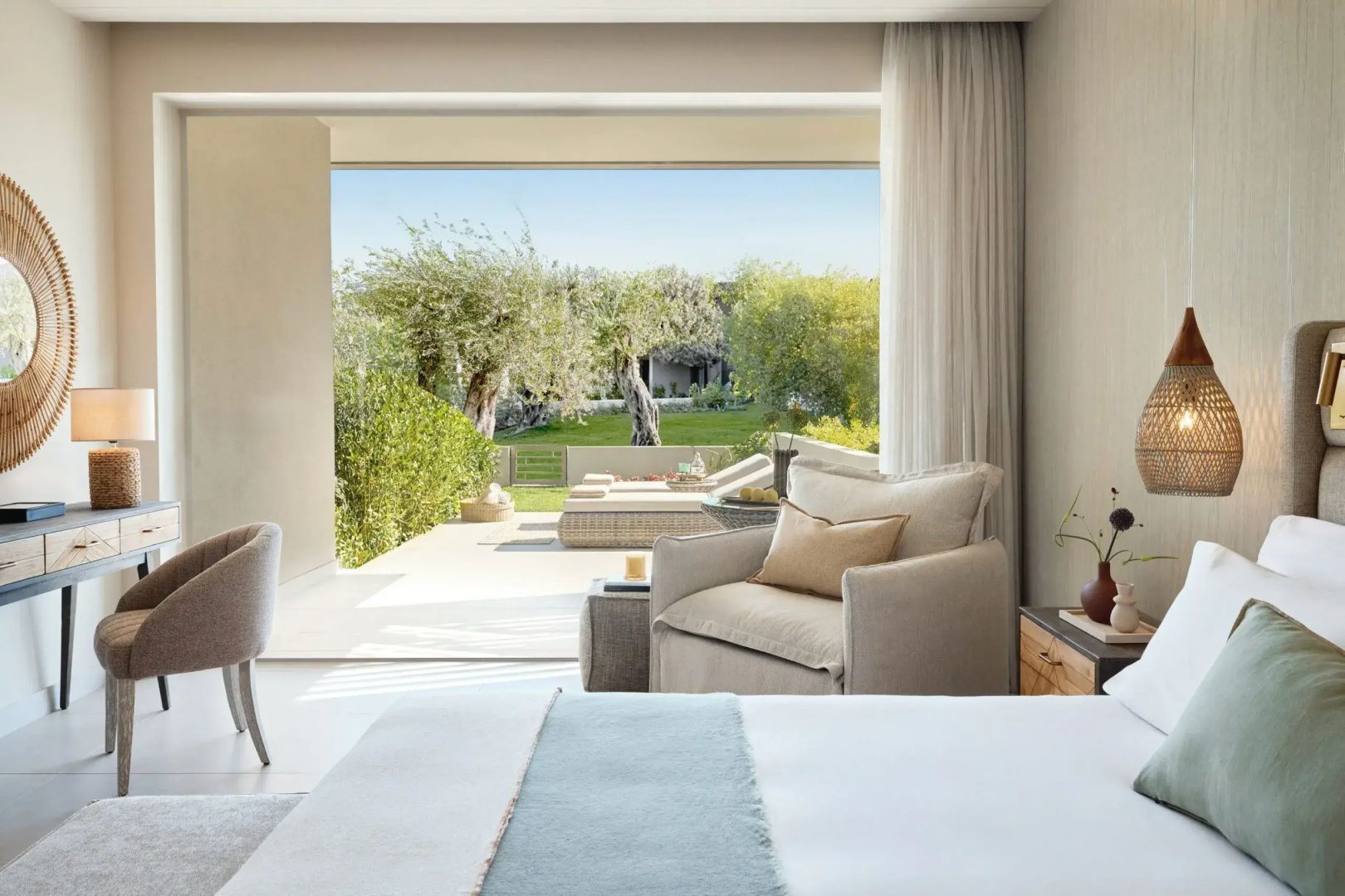 Blick aus dem Schlafzimmer auf eine sonnige Terrasse und den grünen Garten.