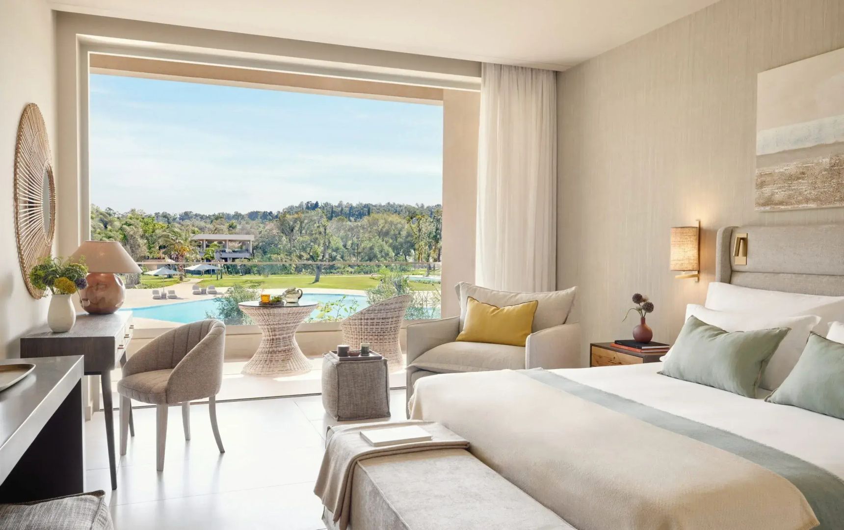 Hotelzimmer mit Balkon und Blick auf die Poolanlage und grüne Landschaft.