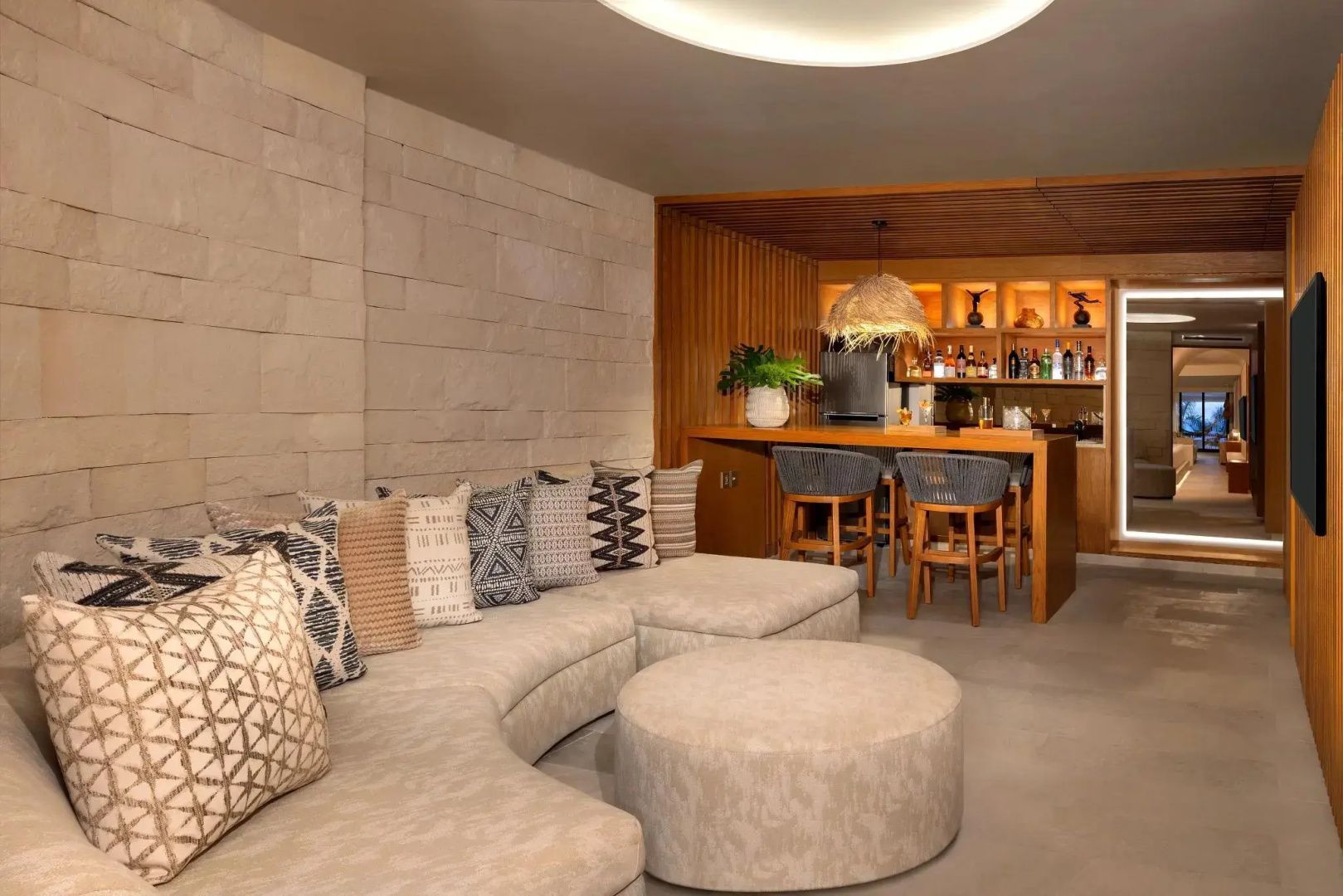 Wohnbereich mit einem gebogenen Sofa, Kissen und einer Theke mit Barhockern.