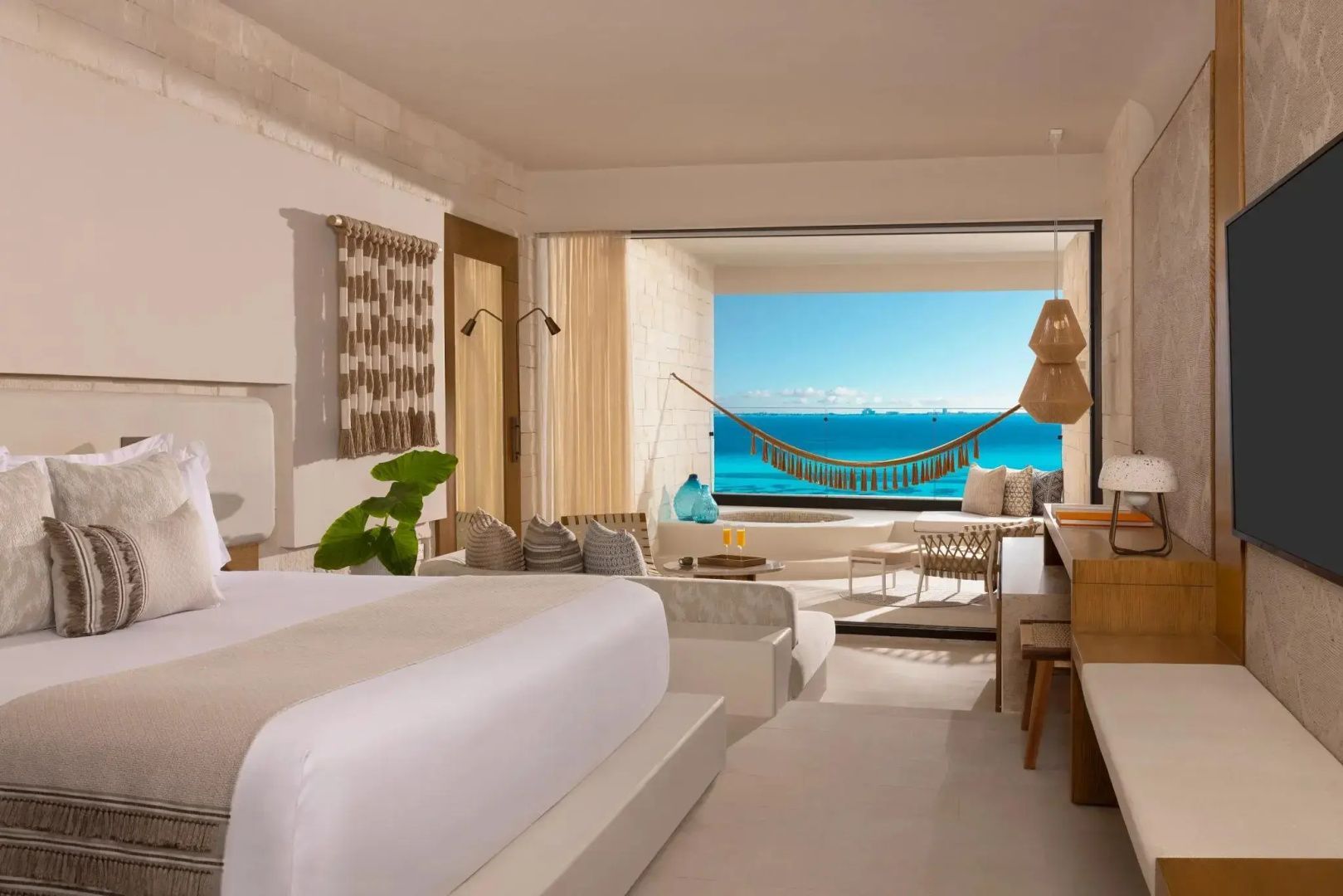 Sicht aus dem Hotelzimmer über den Balkon mit Hängematte direkt auf das türkisfarbene Meer.
