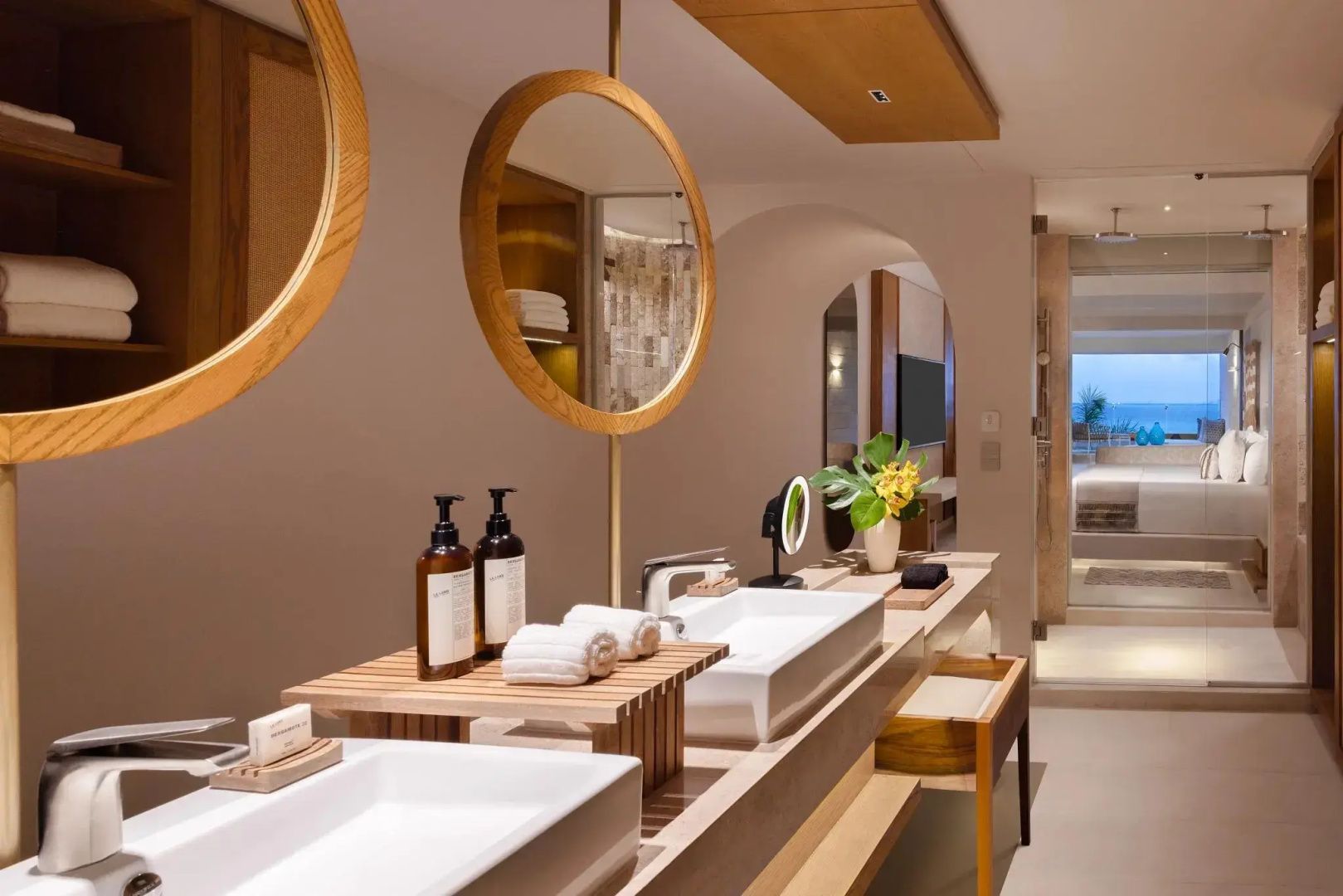 Badezimmer mit doppeltem Waschtisch, zwei runden Spiegeln und Pflegeprodukten aus Holz.