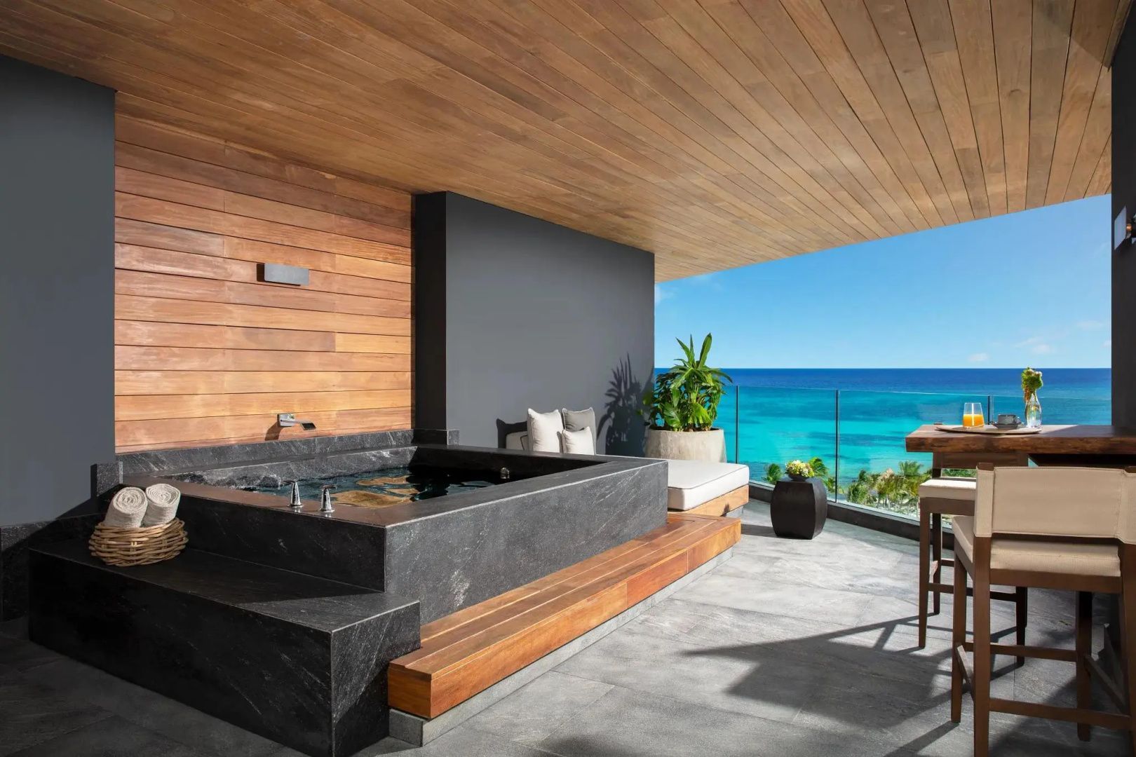 Überdachter Balkon mit Whirlpool, Sitzgelegenheiten und direktem Meerblick.