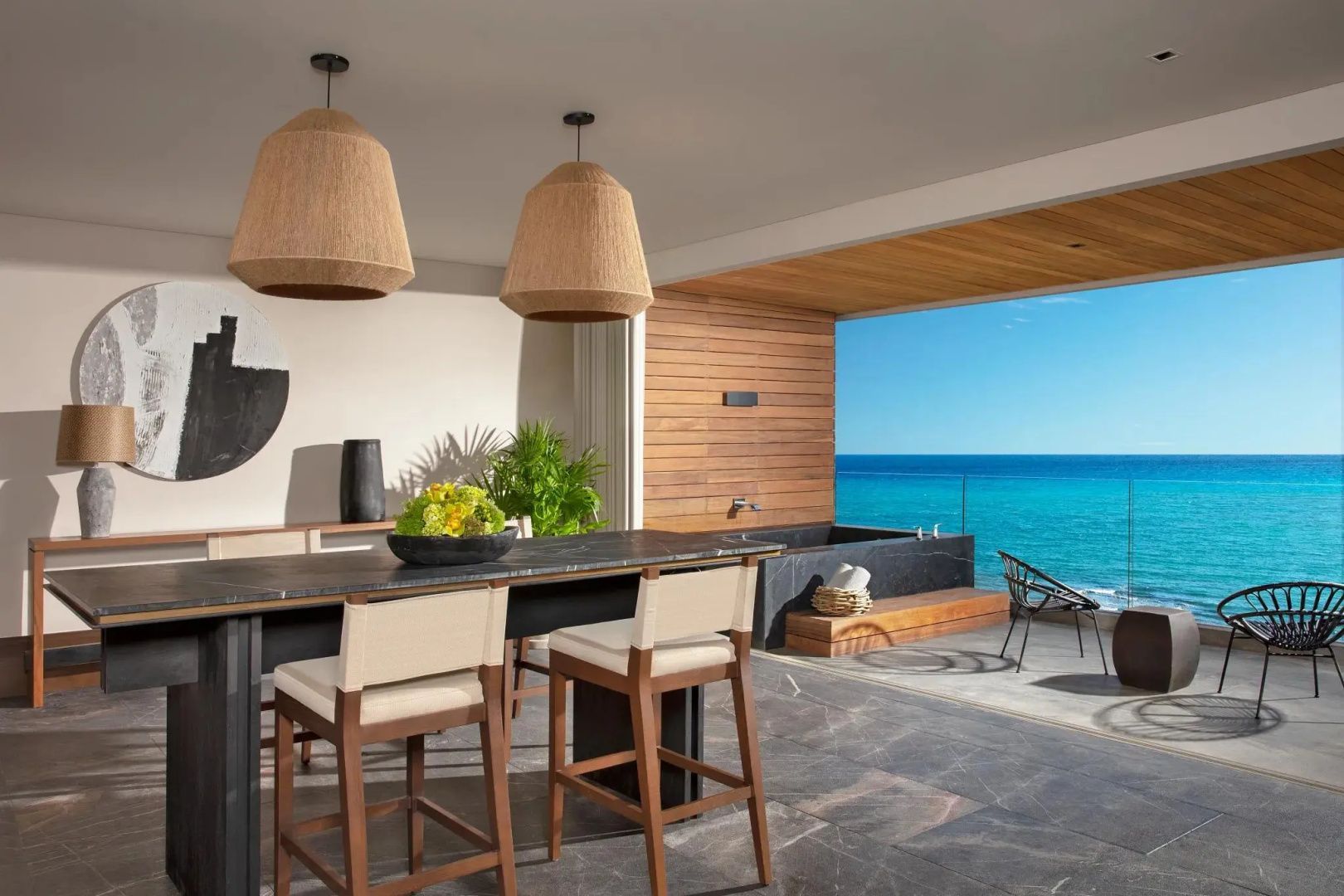 Essbereich in einer Suite mit Barstühlen und offener Terrasse mit Blick auf das blaue Meer.