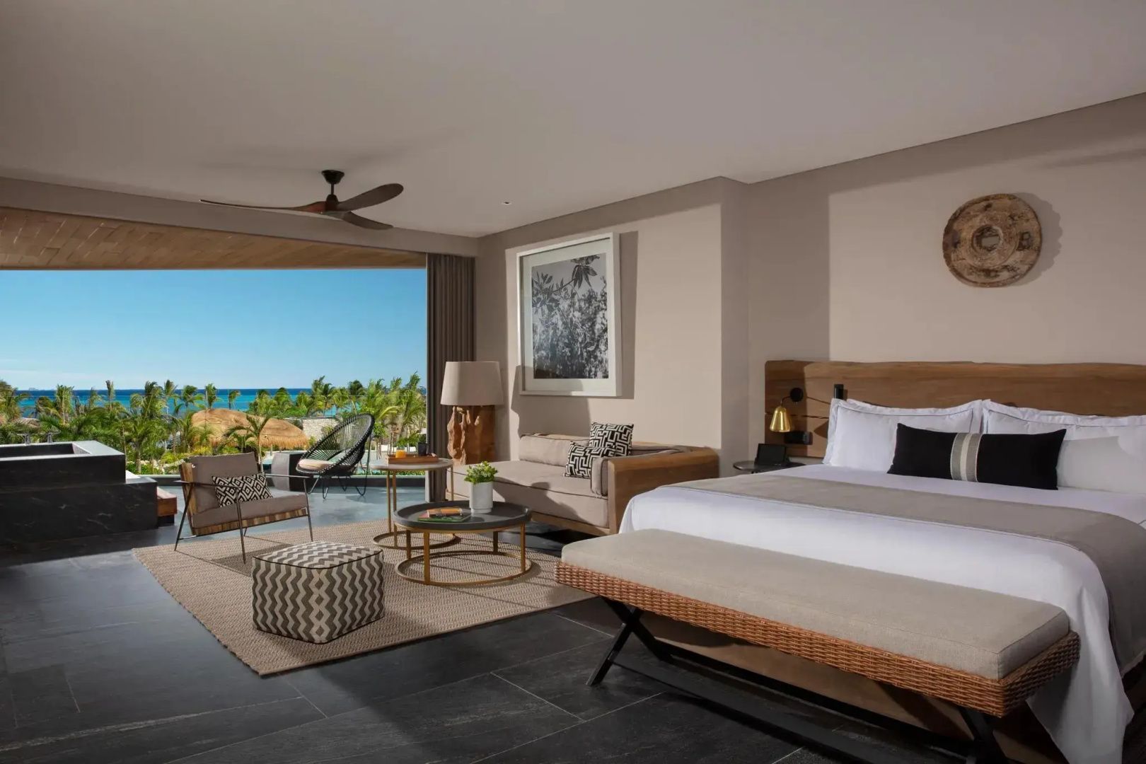Schlafbereich einer Suite mit Doppelbett, Sitzgruppe und Zugang zum Balkon mit Meerblick.