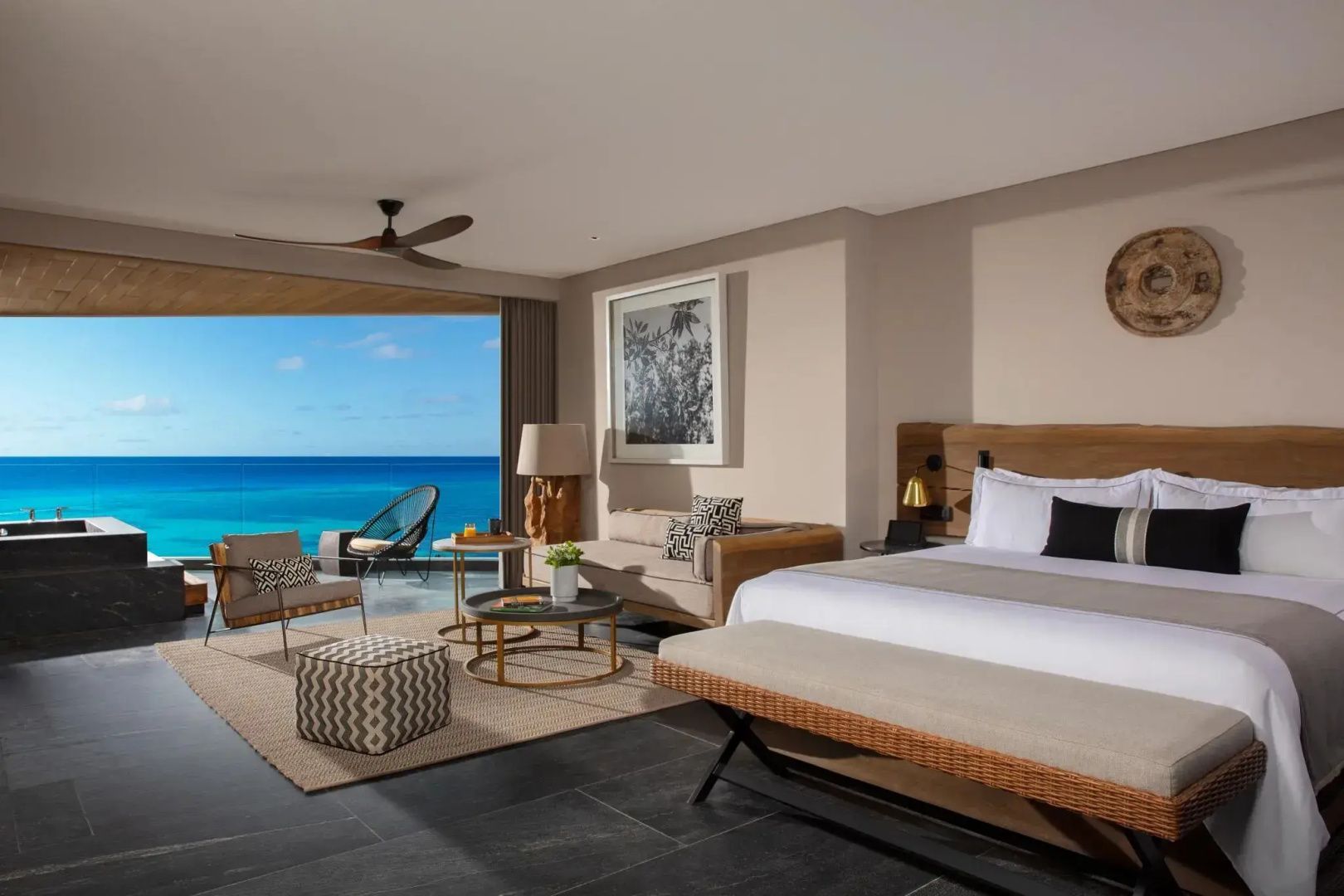 Hotelzimmer mit Doppelbett, Sitzbereich und Balkon mit weitem Blick auf das blaue Meer.