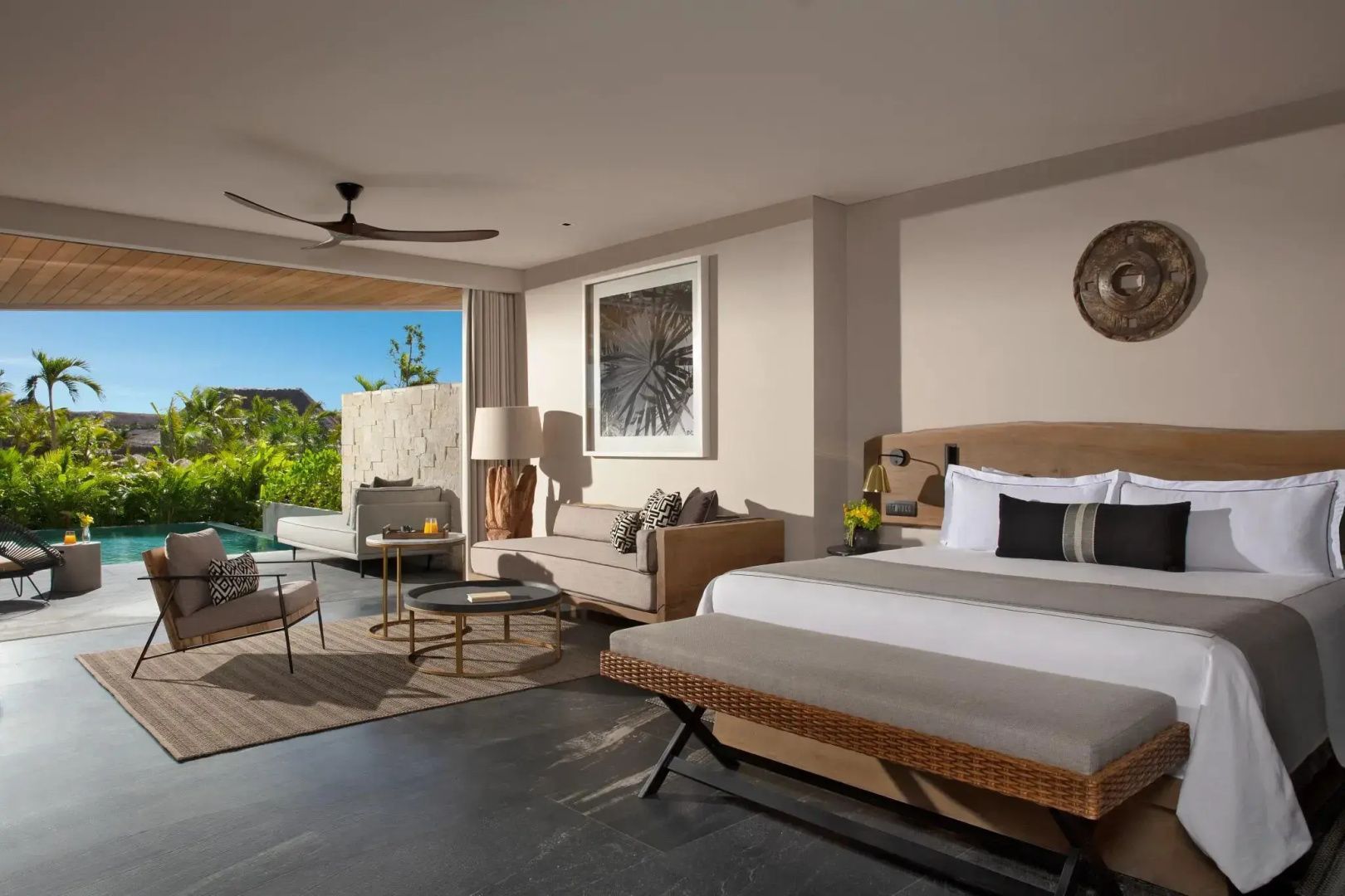 Schlafzimmer mit Kingsize Bett, Sitzbereich und Zugang zur privaten Terrasse mit Pool.