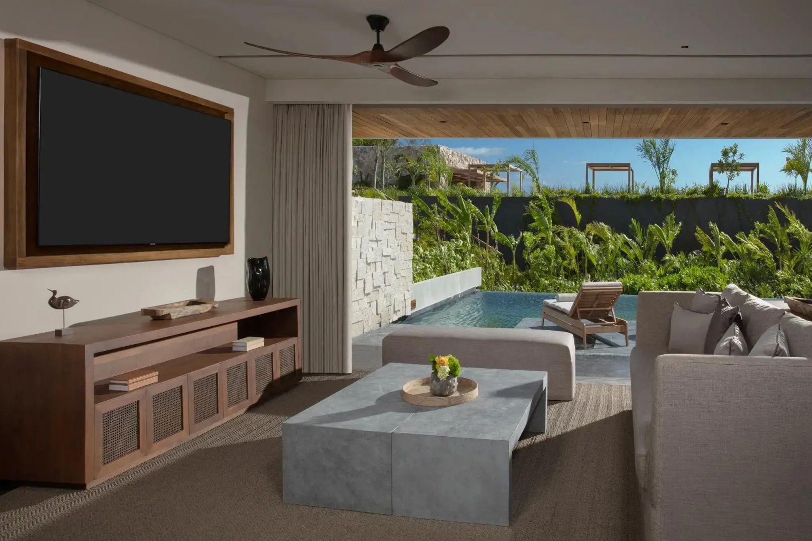 Wohnzimmer einer Suite mit Blick auf die eigene Terrasse und einen kleinen Pool.