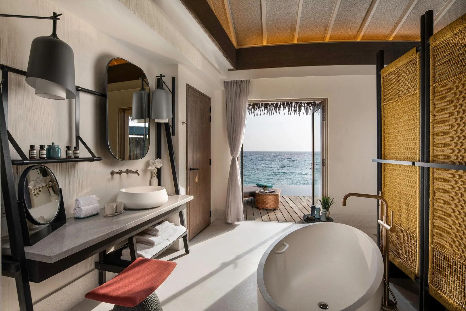 Badezimmer mit freistehender Badewanne, Waschbecken und Zugang zur Terrasse.