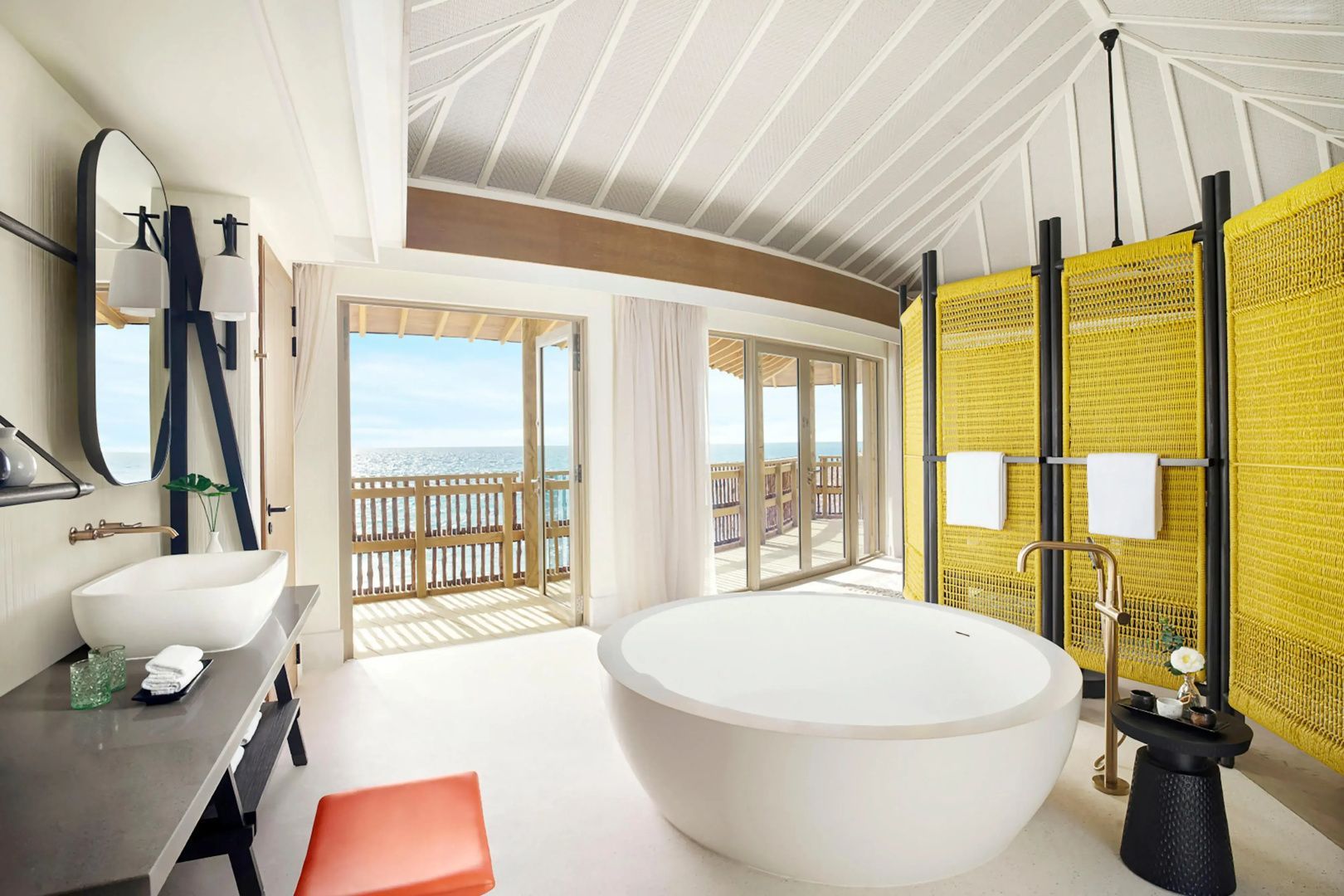 Badezimmer mit freistehender runder Badewanne und großen Fenstern mit Meerblick.