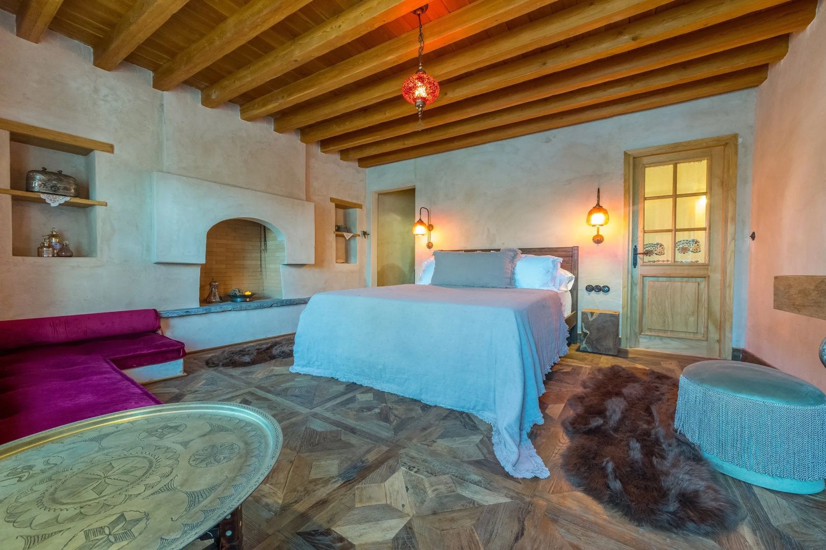Rustikales Schlafzimmer mit Holzbalkendecke, Kamin und Doppelbett.