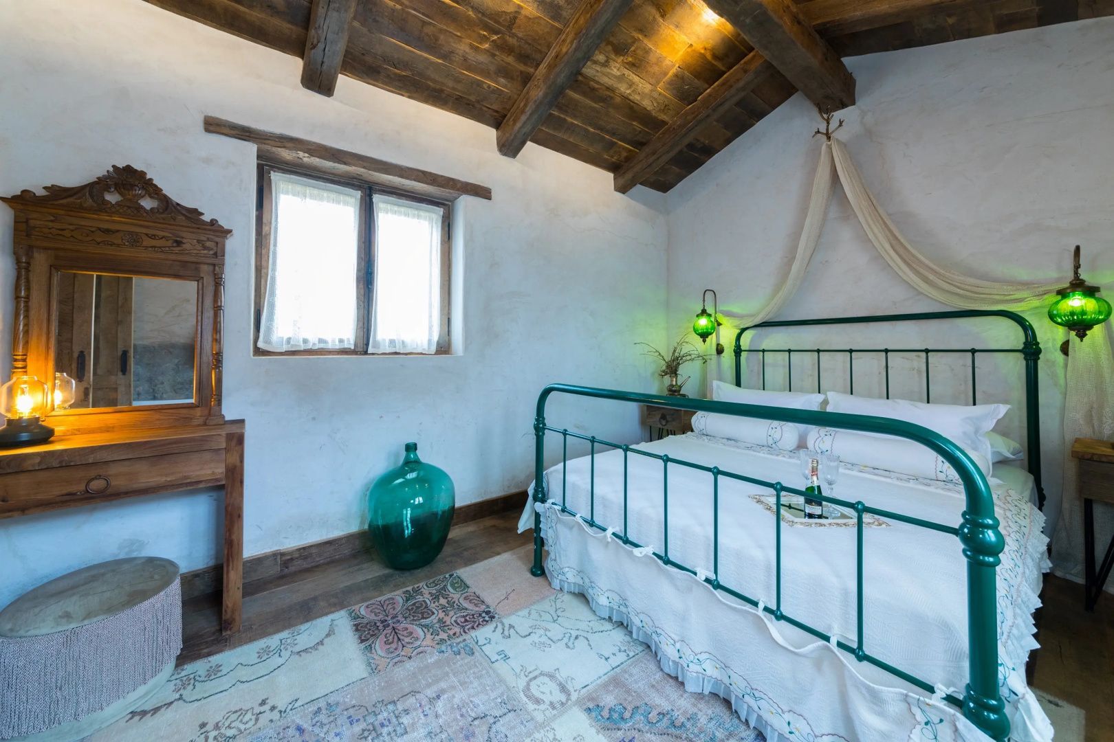 Schlafzimmer mit grünem Metallbett, Holzdecke und rustikaler Einrichtung